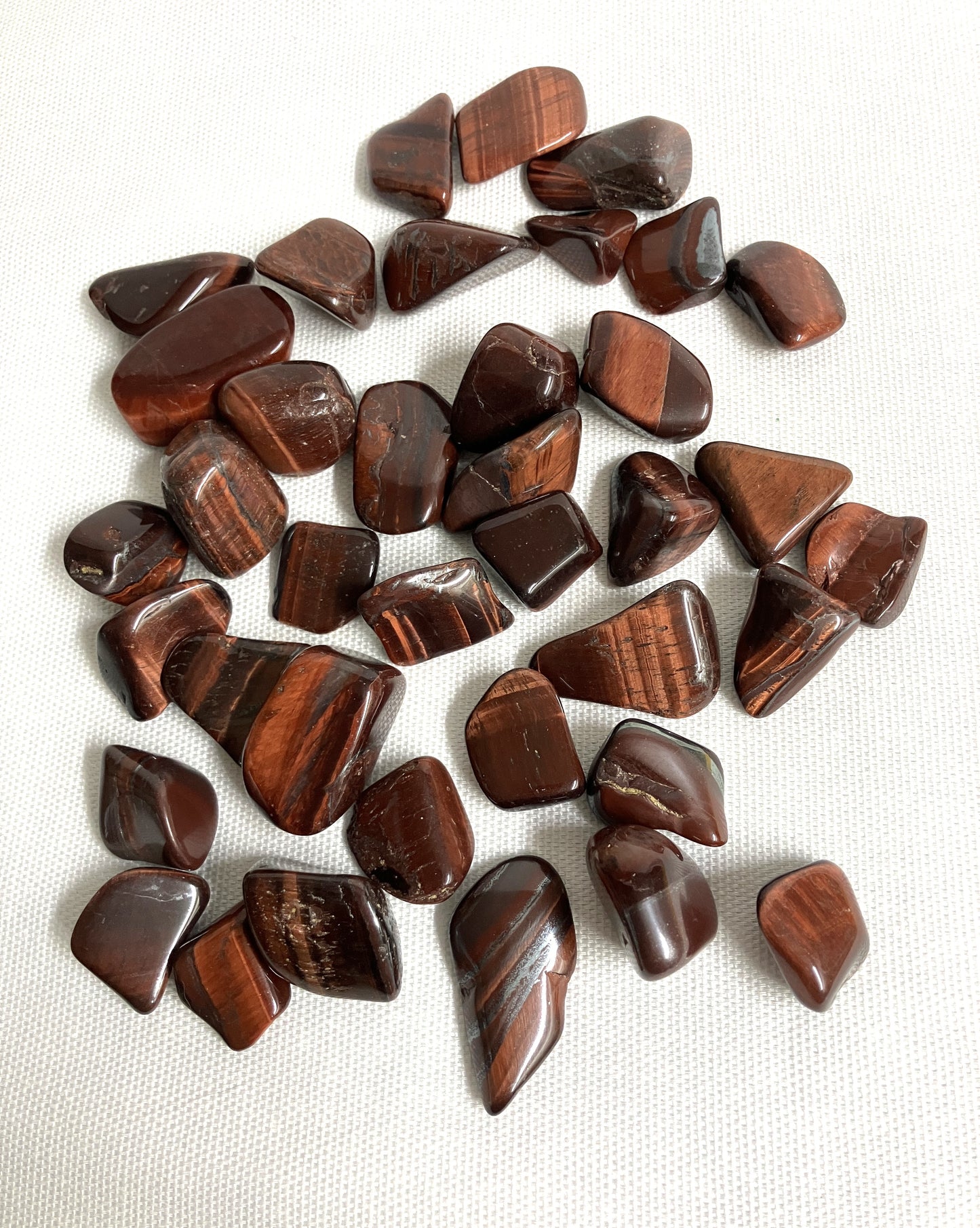 Red Tiger Eye tumbled crystals showing the variety of patterns and styles
