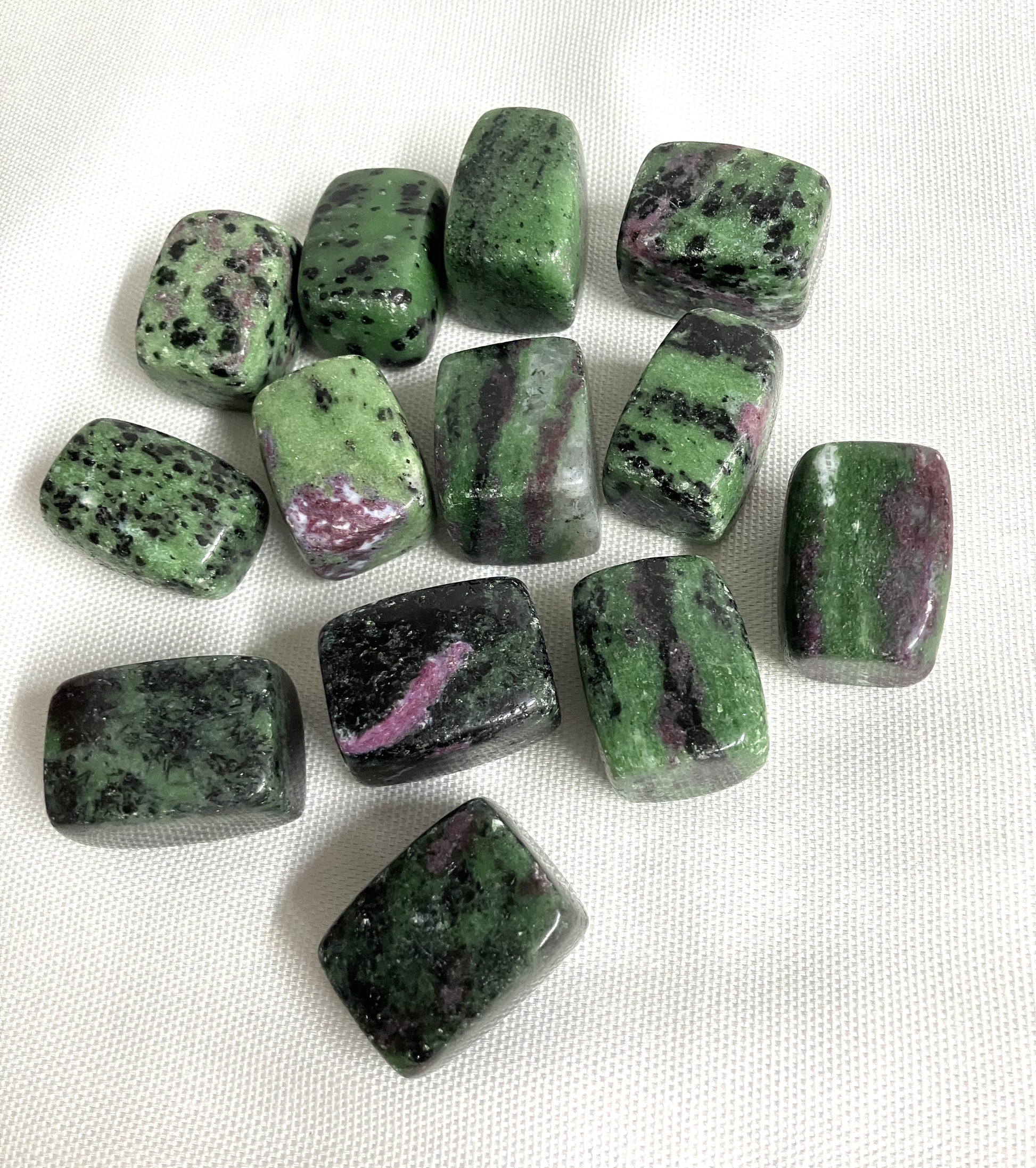 Tumbled Ruby in Zoisite Crystals on a white fabric background