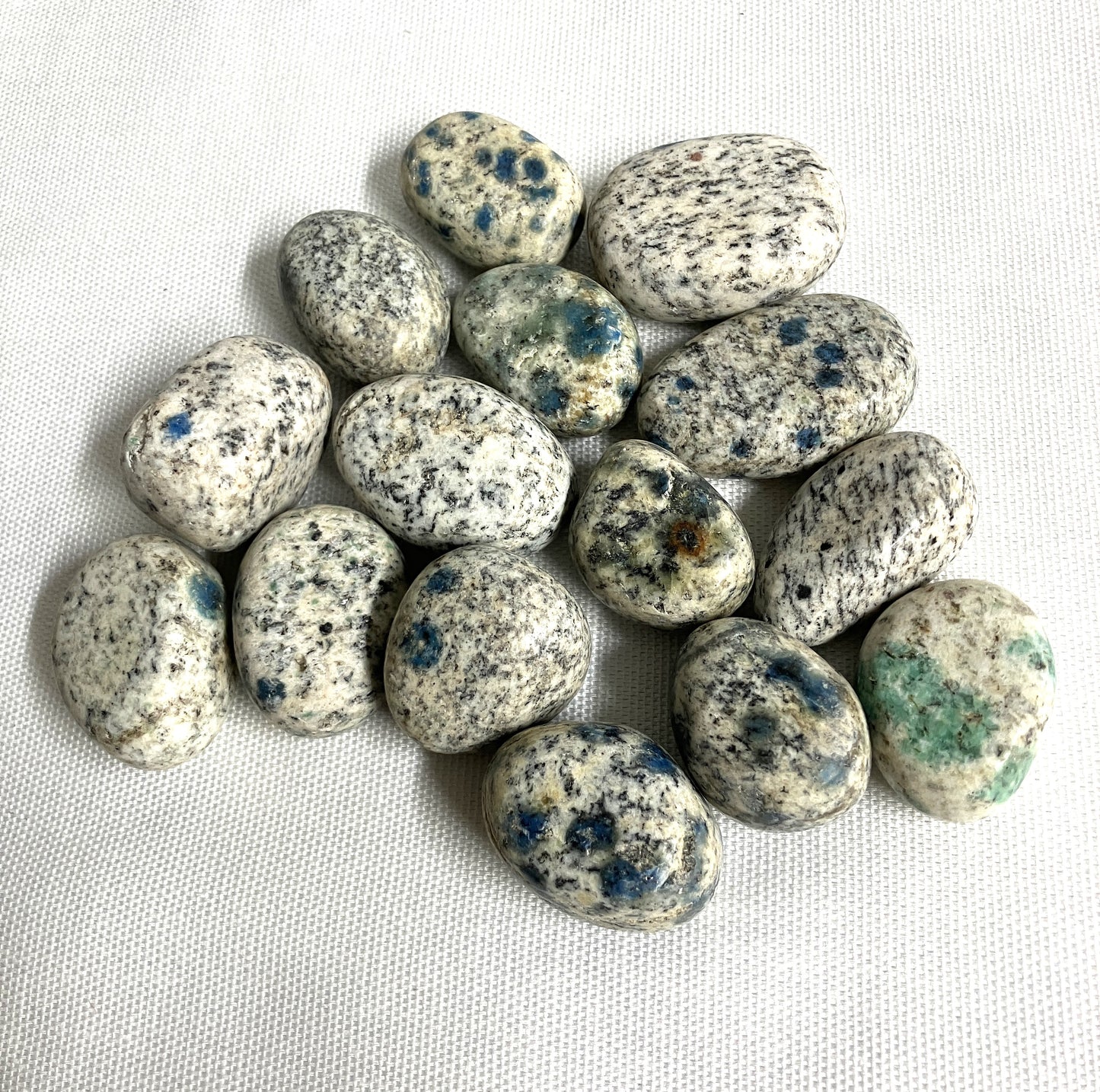 Front side of K2 Crystals with blue speckles on a white fabric background