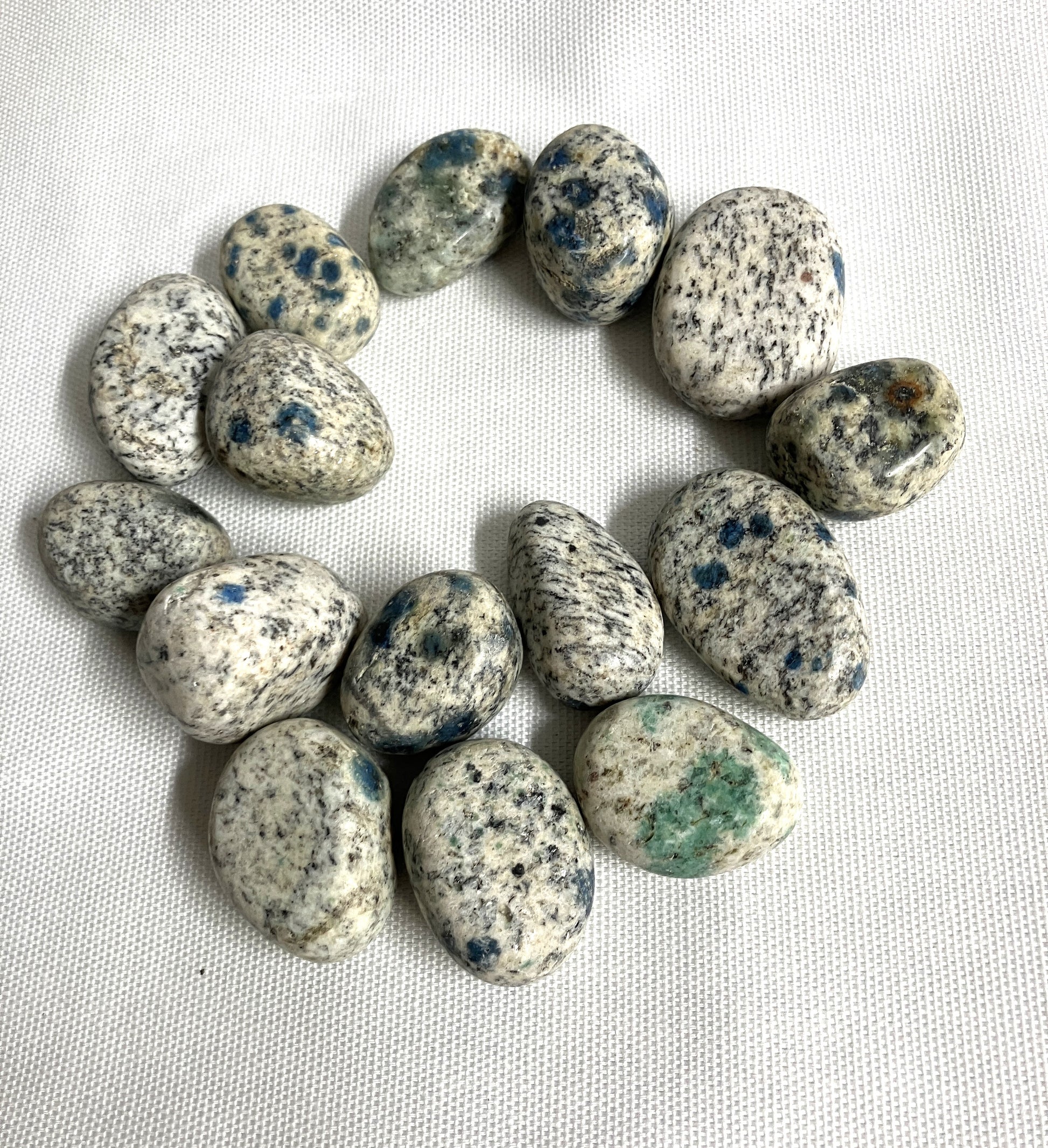 Large group of K2 Crystals showing the speckled pattern on a white fabric background 