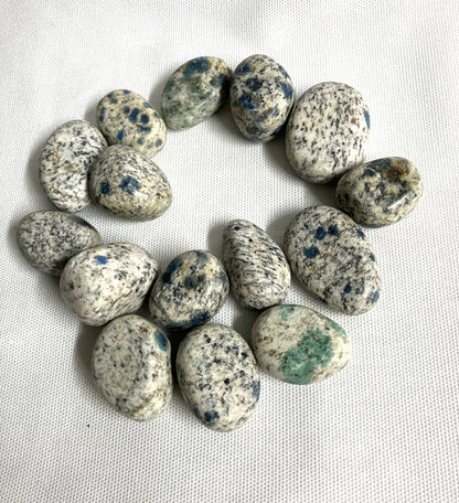 Large group of K2 Crystals showing the speckled pattern on a white fabric background 