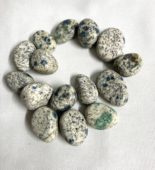 Large group of K2 Crystals showing the speckled pattern on a white fabric background 