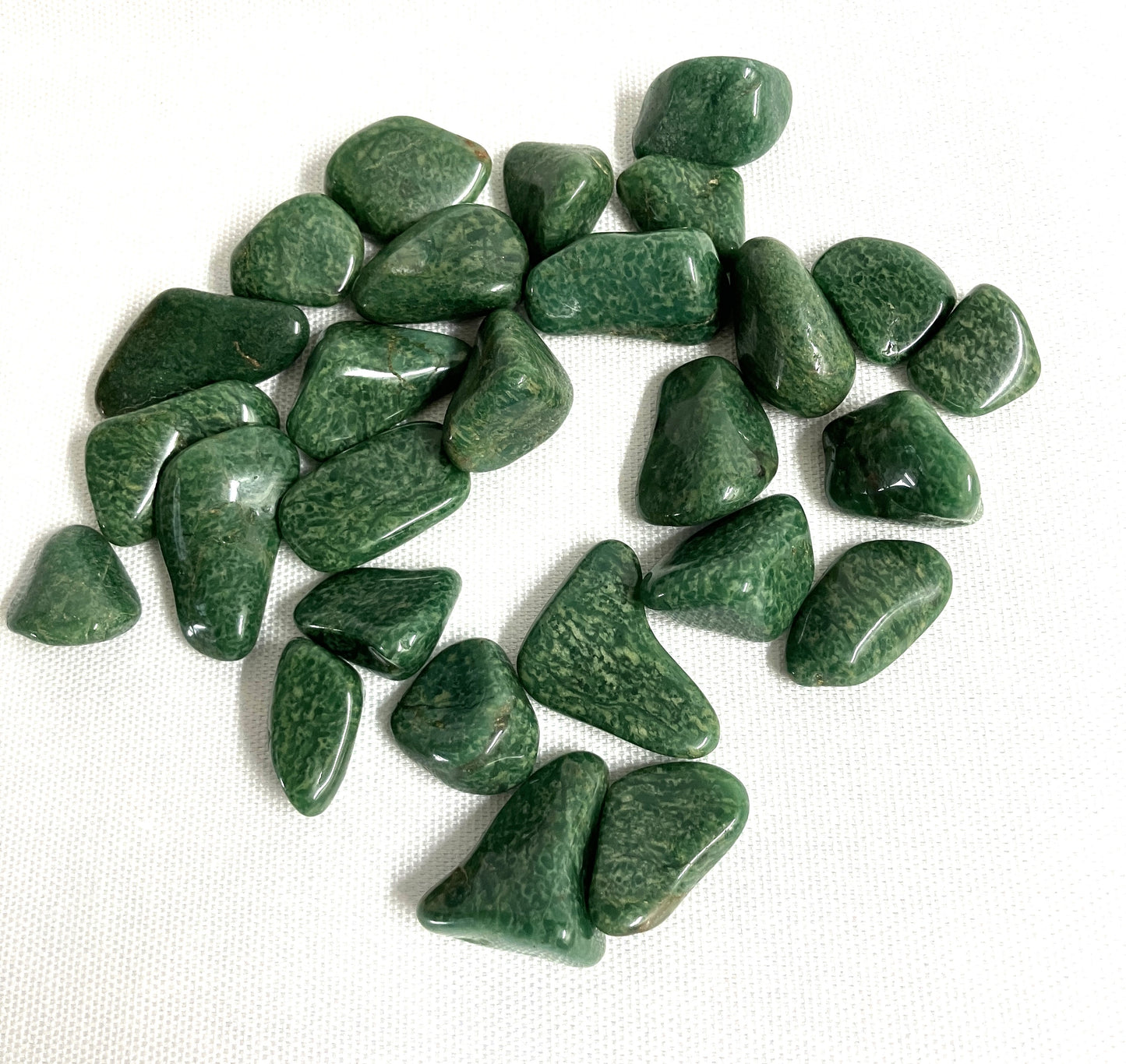 Tumbled Verde Quartz Crystals on a white fabric background