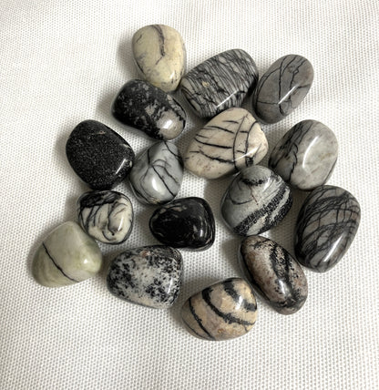 Tumbled Spider Web Jasper Crystals on a white fabric background