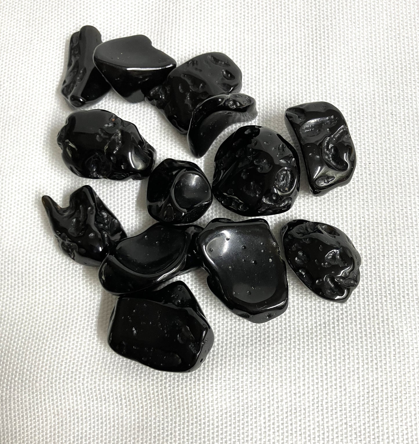 Tektite Stones showing the assorted sizes on a textured white surface