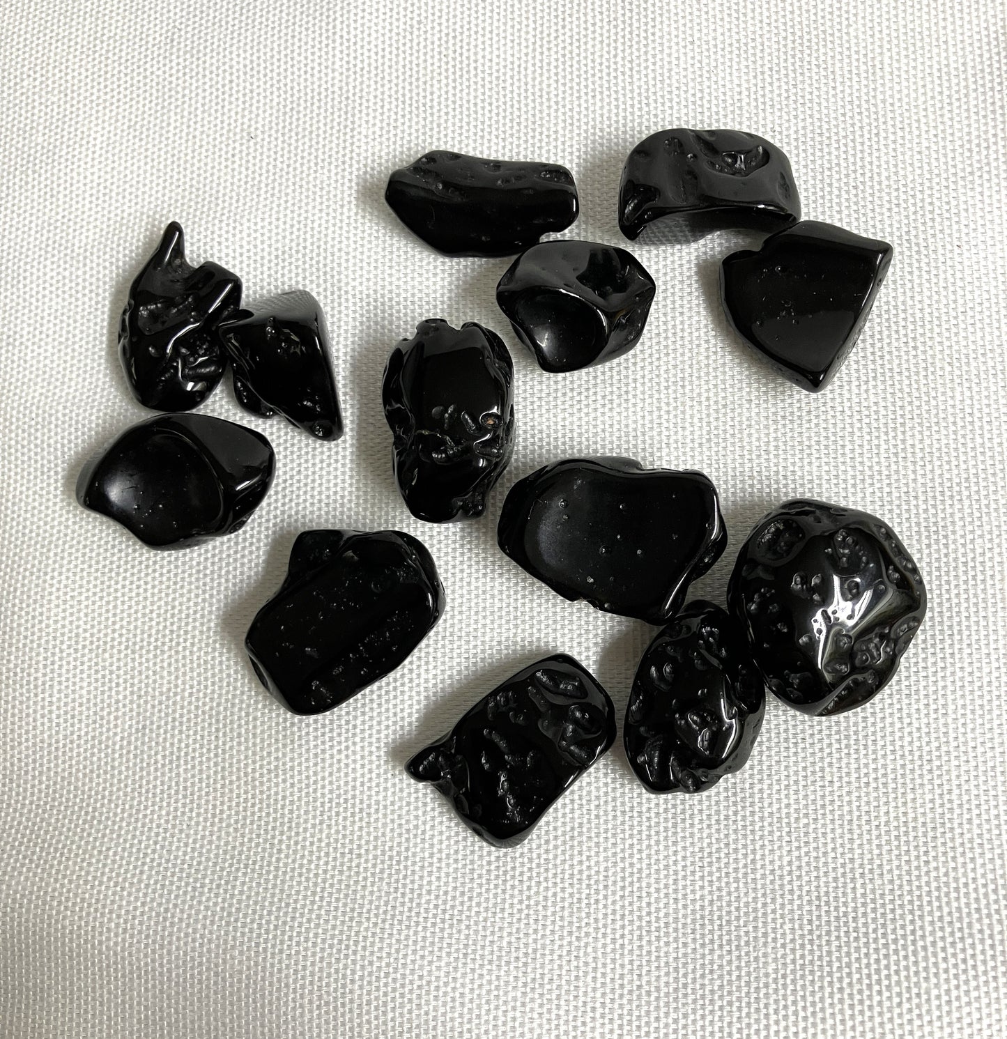 Tumbled Tektite Stones on a white fabric background