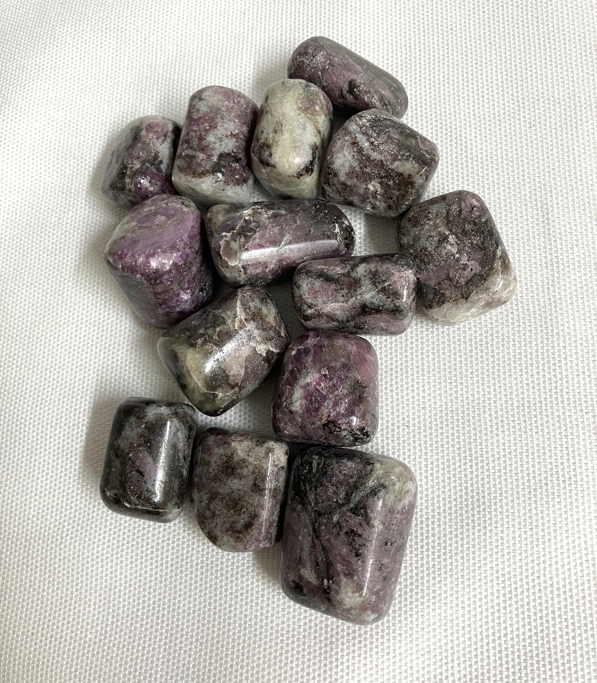 Bottom side of Pink Garnet Tumbled Crystals on a white fabric background