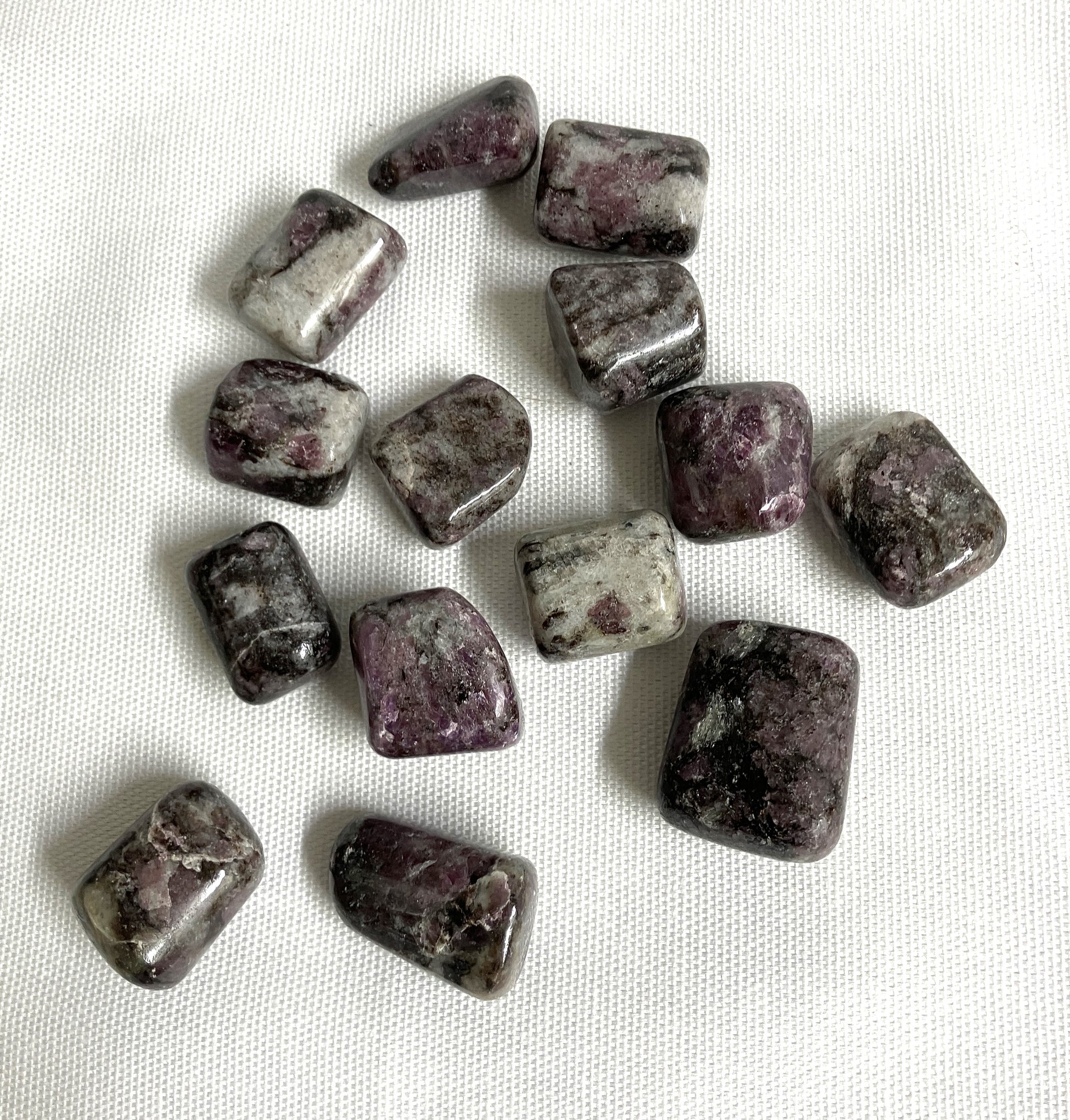 Top view of Pink Garnet Tumbled Crystals  on a white fabric background