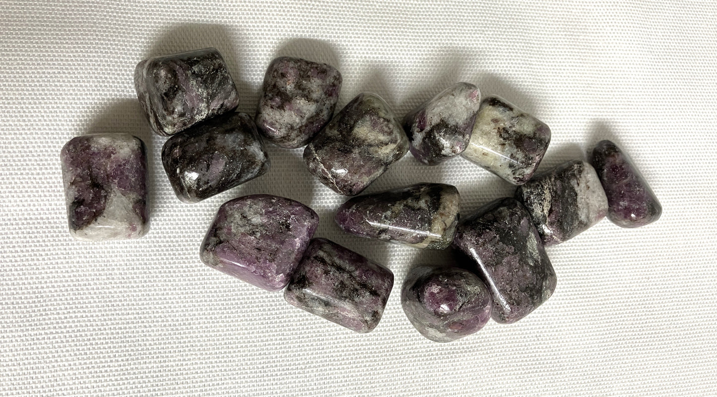 Closeup of Pink Garnet Tumbled Crystals on a textured white surface