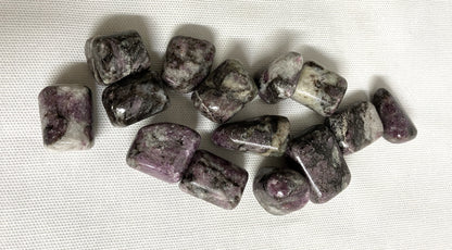 Closeup of Pink Garnet Tumbled Crystals on a textured white surface