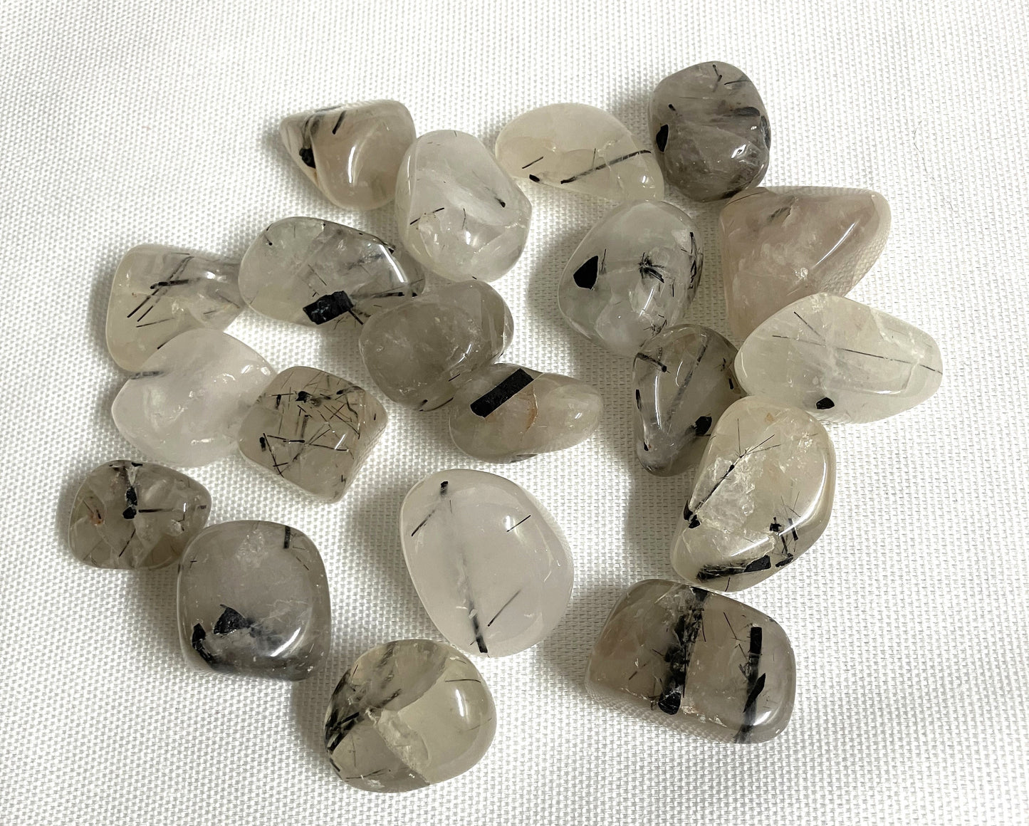 Tourmalinated Quartz Crystals crystals with black inclusions on a white fabric background