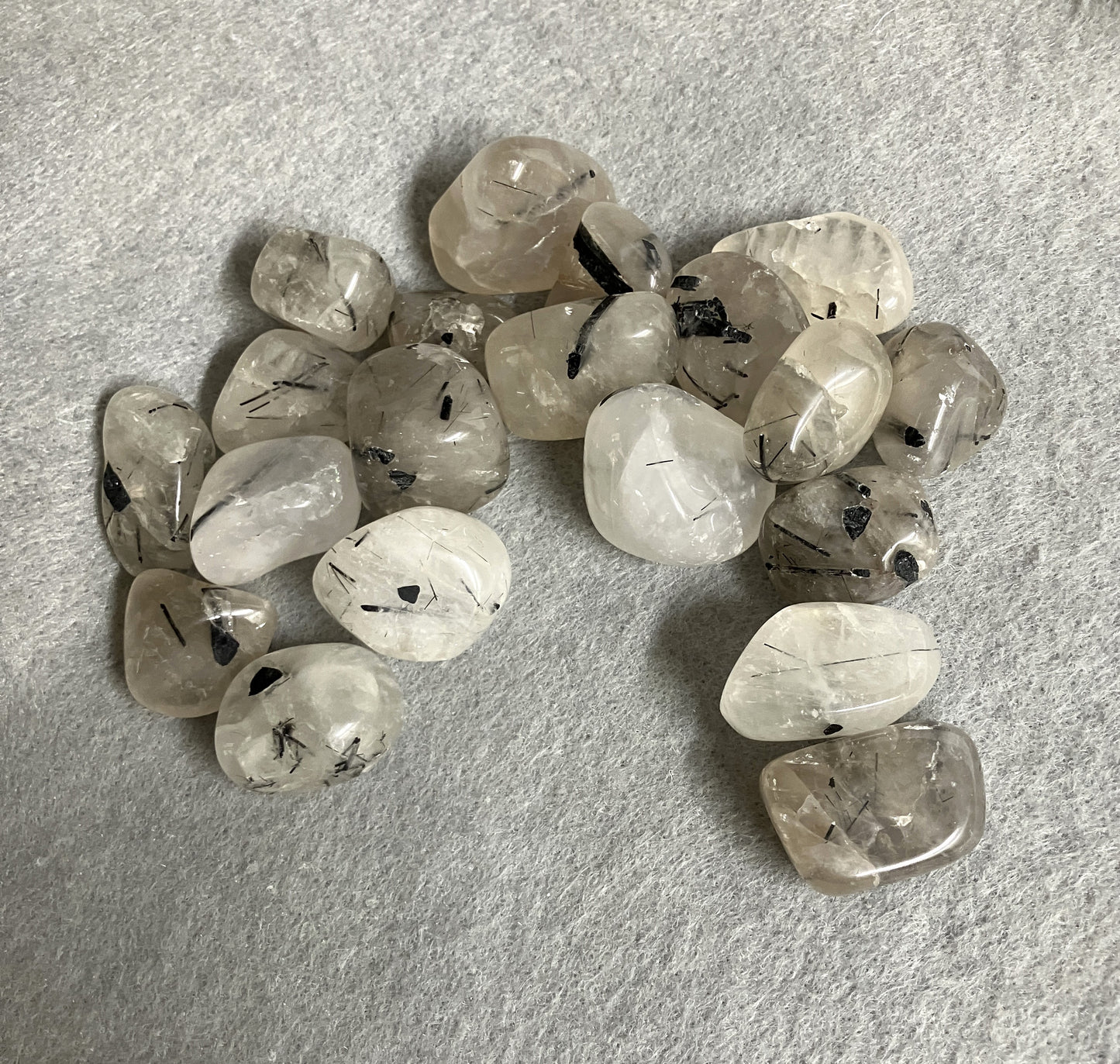 Grouping of Tourmalinated Quartz Crystals on a gray surface