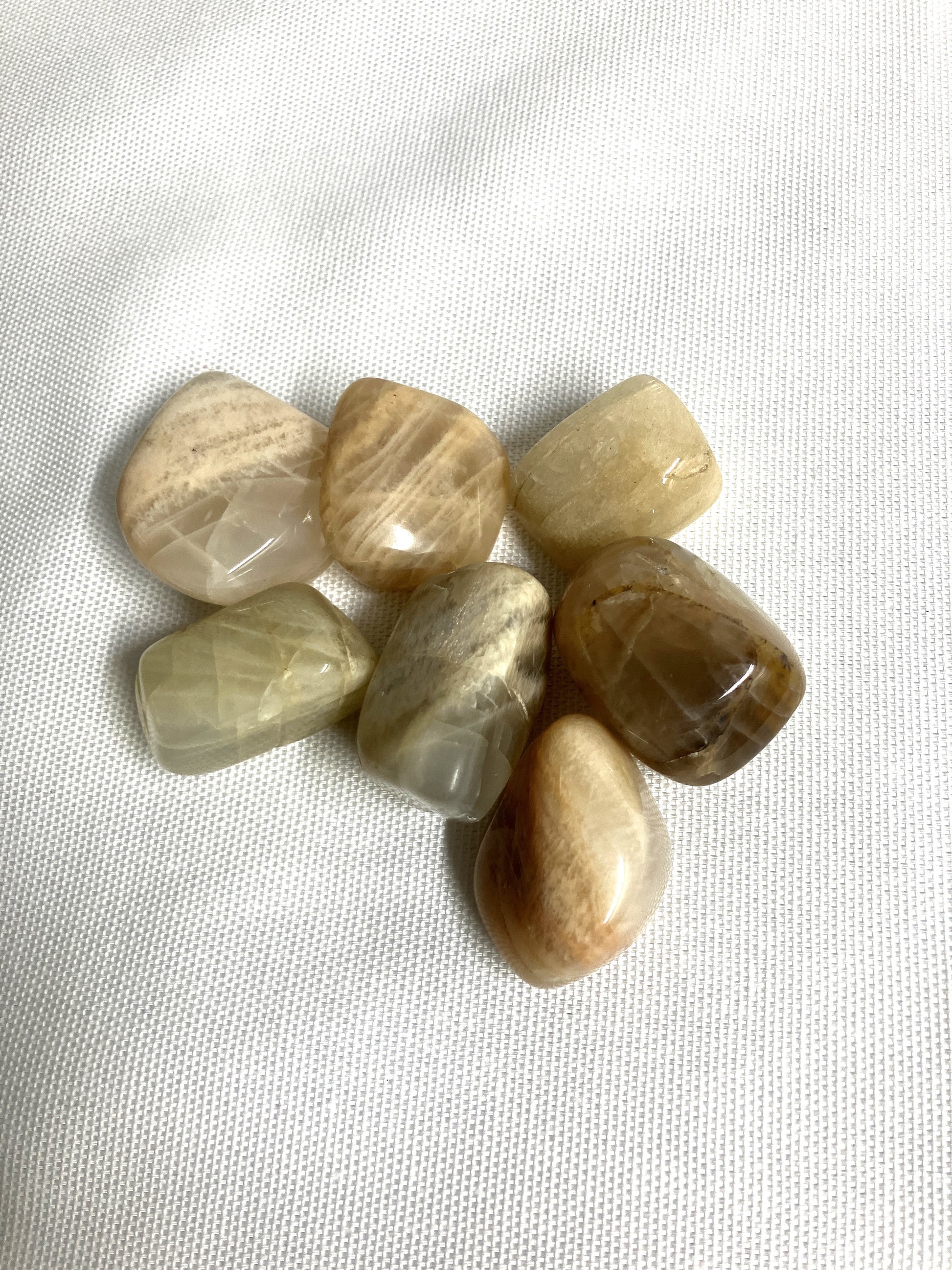 Collection of Tumbled Moonstone Crystals on a white fabric background