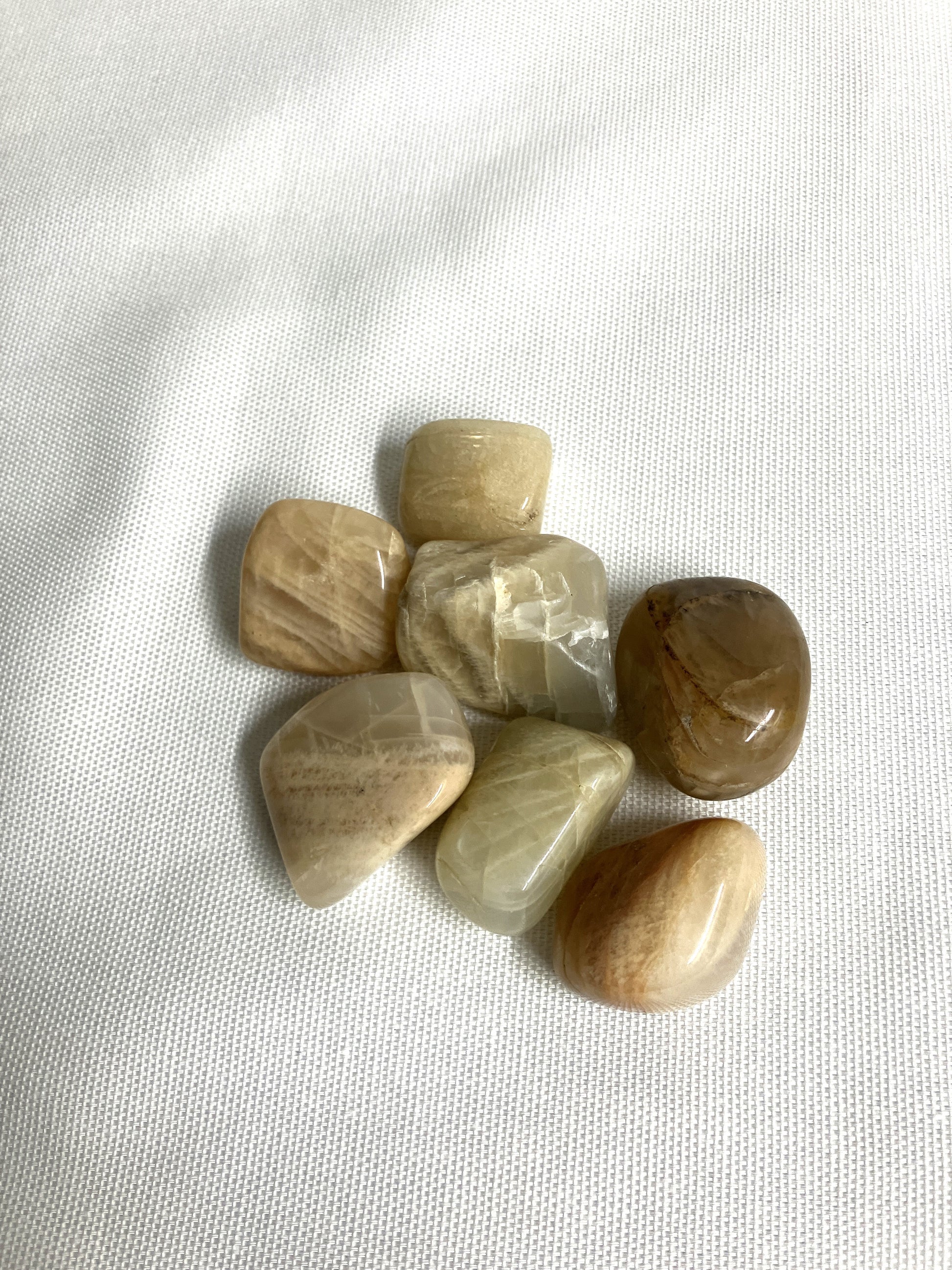 Tumbled Moonstone Crystals on a white fabric background