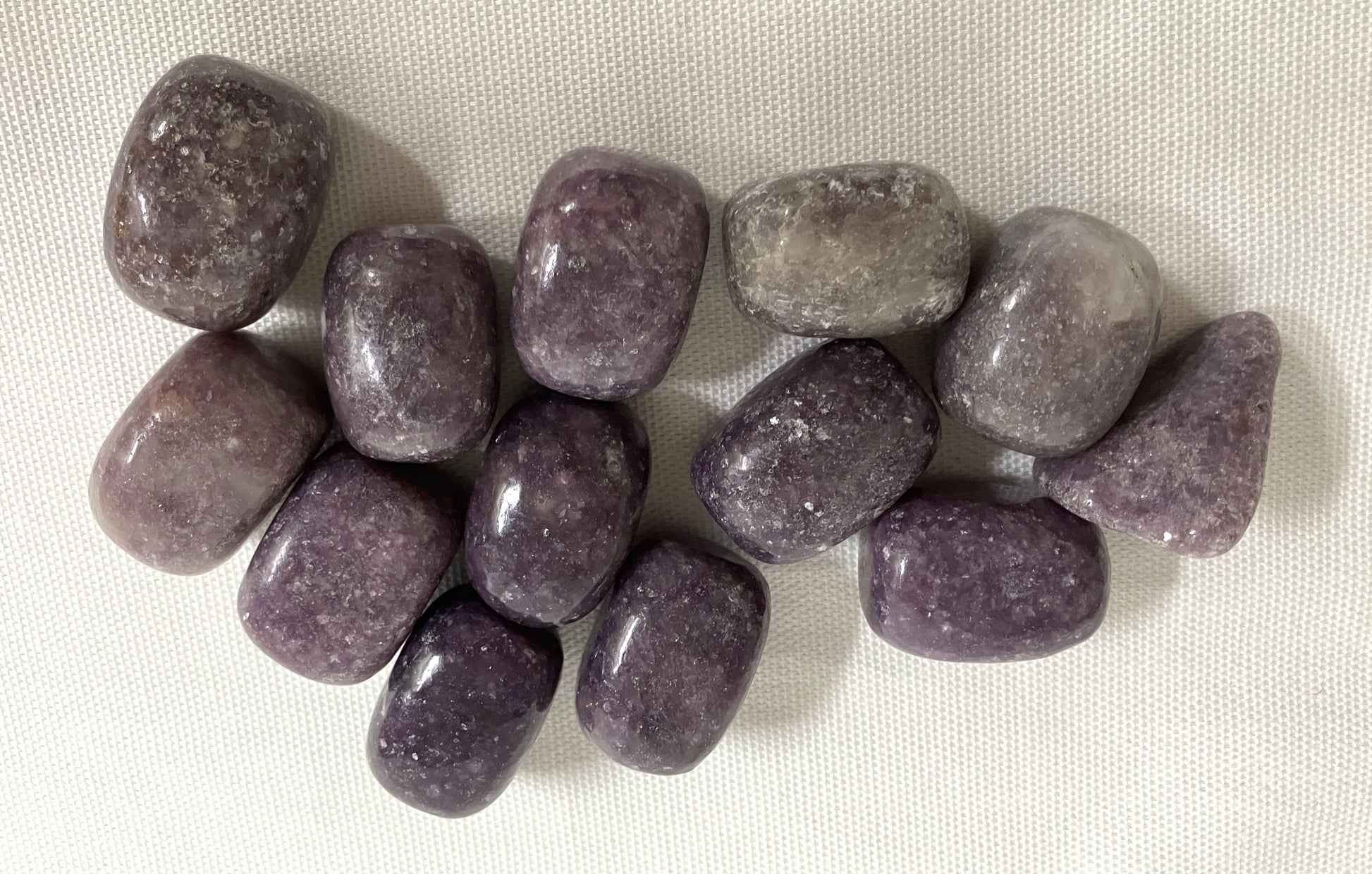 Lepidolite Crystals shown on a white fabric background