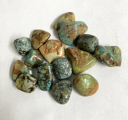 African Turquoise Crystals showing the variations of color and pattern on a white fabric background