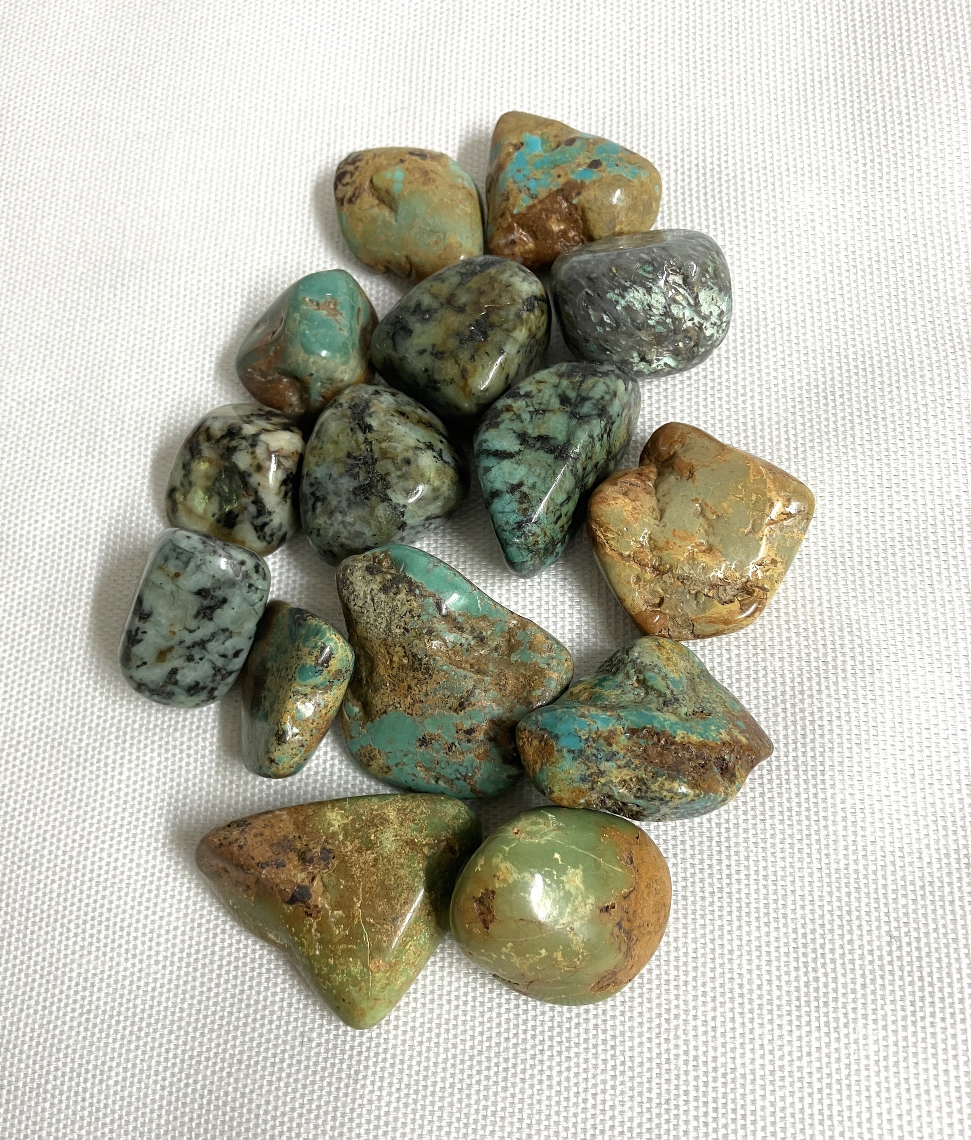 Tumbled African Turquoise Crystals on a white fabric background