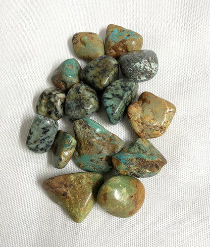 Tumbled African Turquoise Crystals on a white fabric background