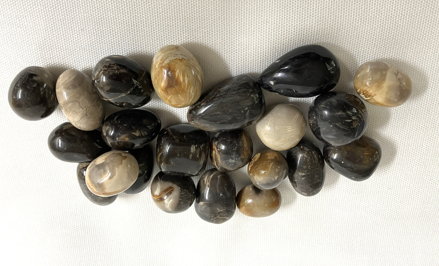 Closeup of Feather Agate Tumbled Crystals on a white fabric background