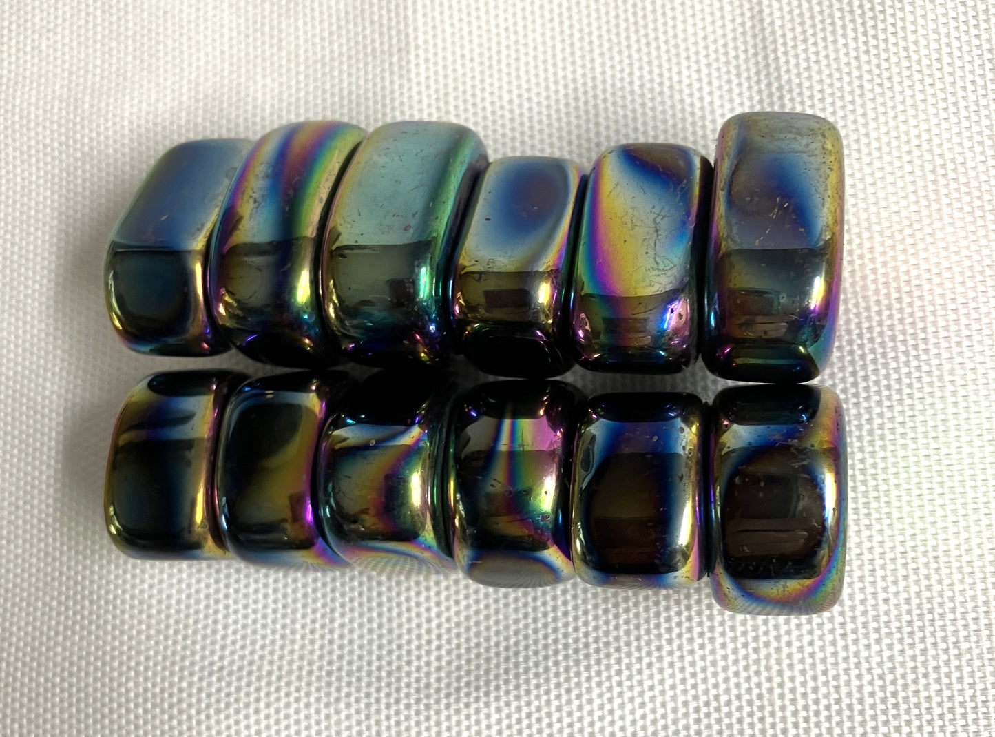 Group of Magnetic Rainbow Hematite Crystals showing the rainbow-like reflection on a textured white background