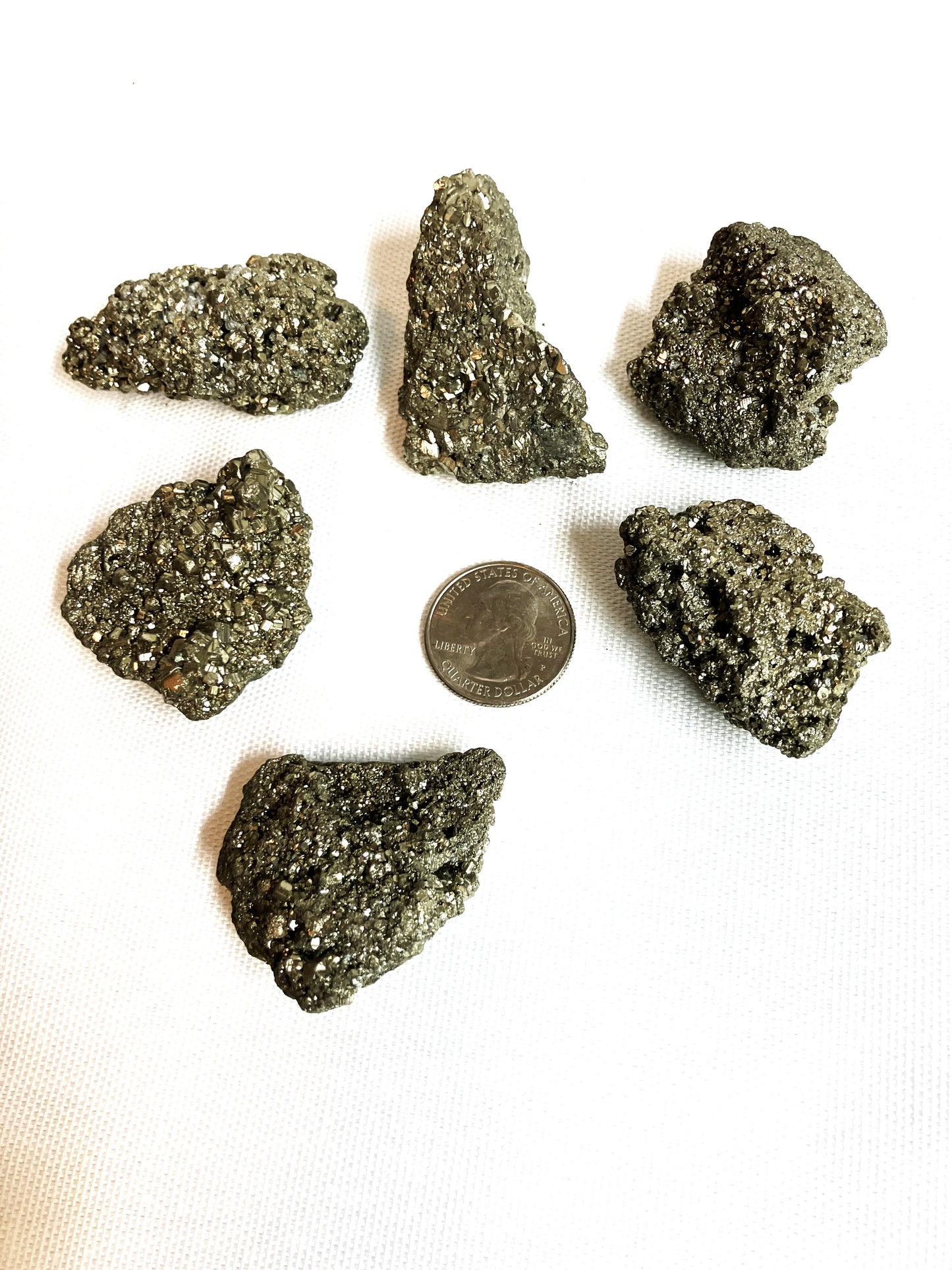 Back side of Natural Pyrite Crystals AKA Fools Gold on a white background with a quarter for scale.