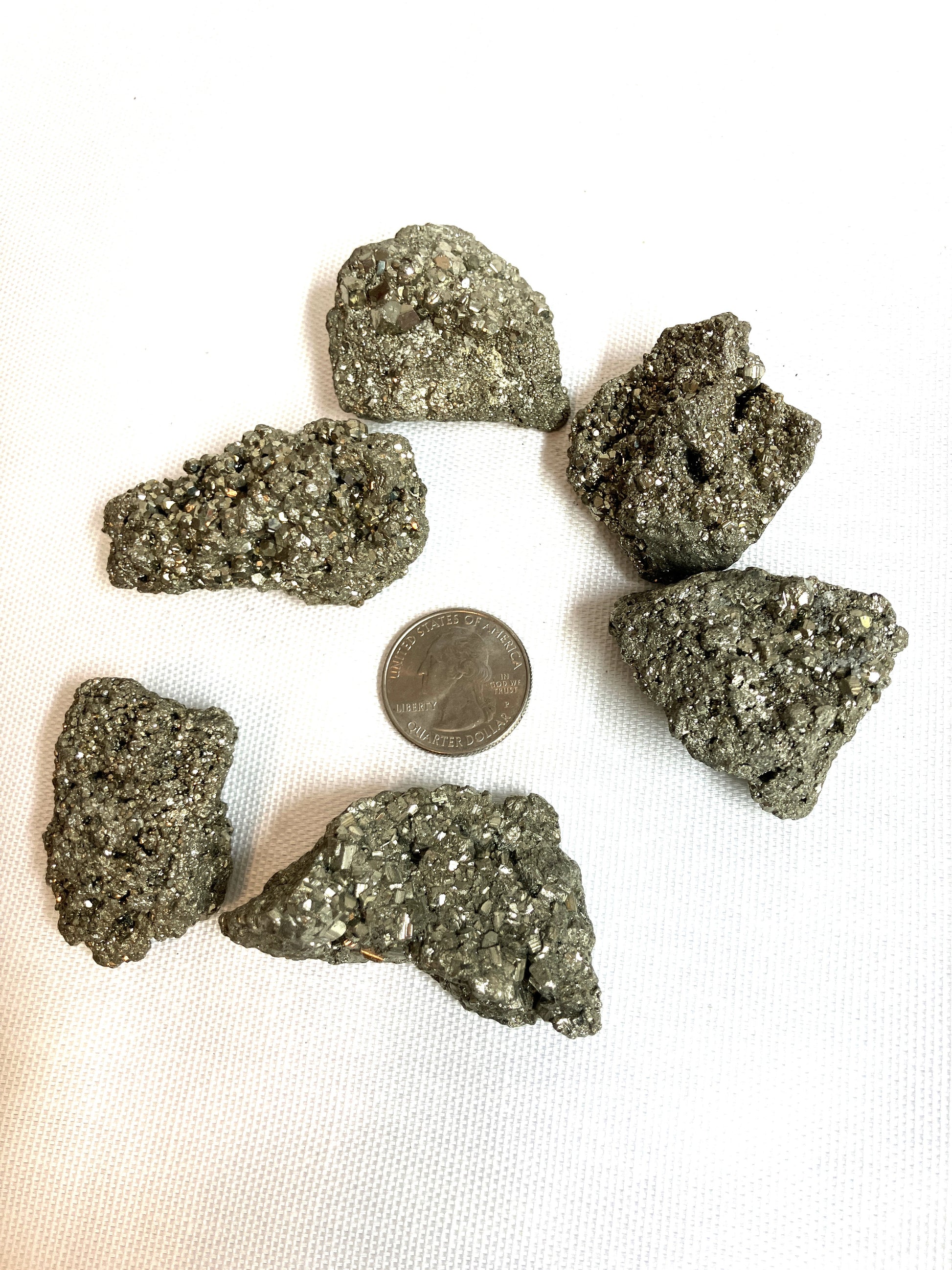 Group of Natural Pyrite Crystals AKA Fools Gold arranged around a quarter for scale on a white background