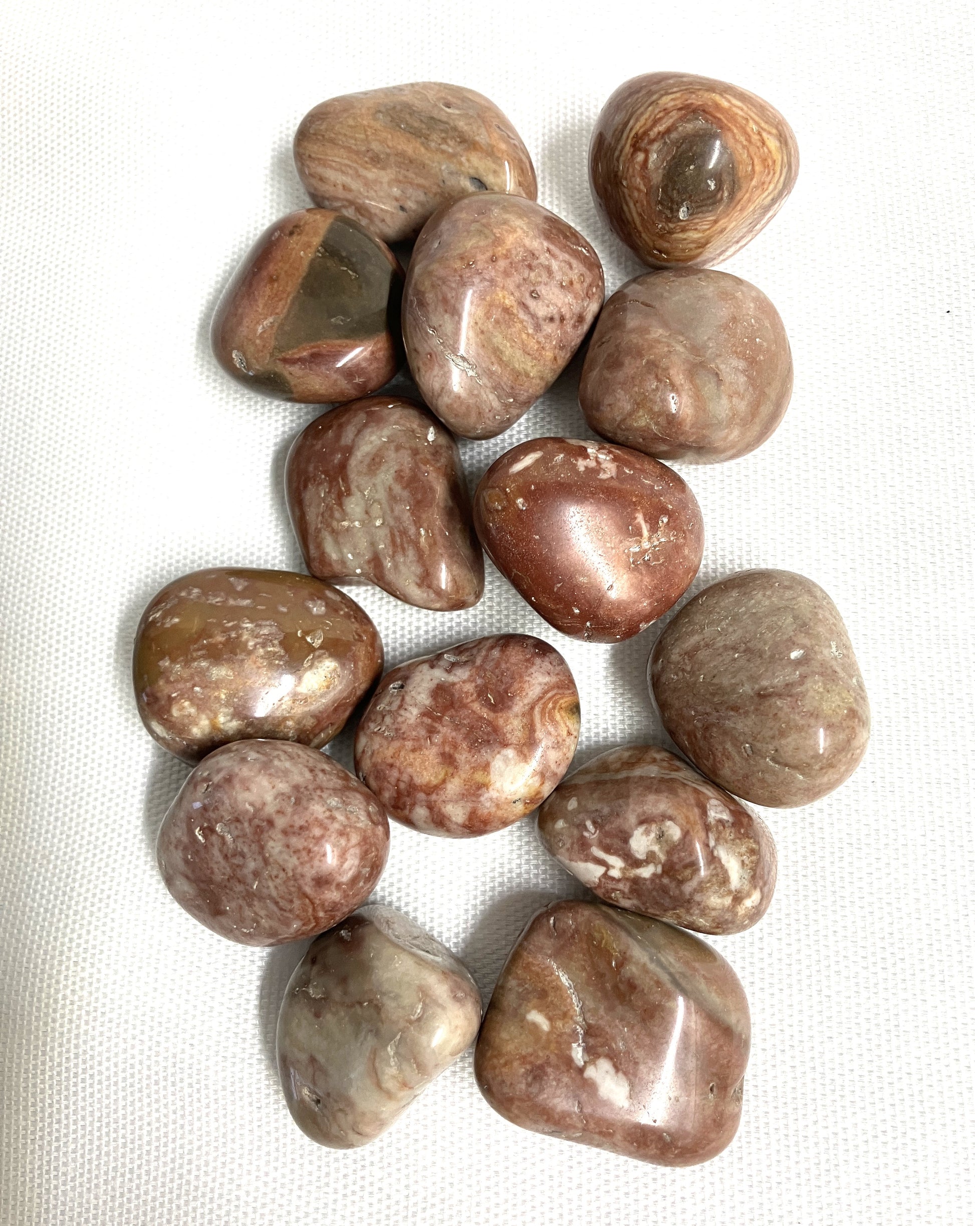 Assorted Crazy Lace Agate Crystals on a white fabric background
