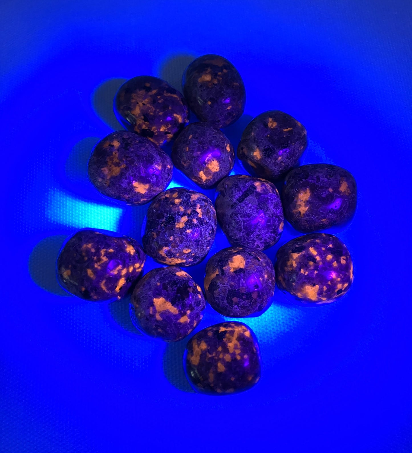 Front side of Flame Crystal AKA Yooperlite shown under UV light on a blue background