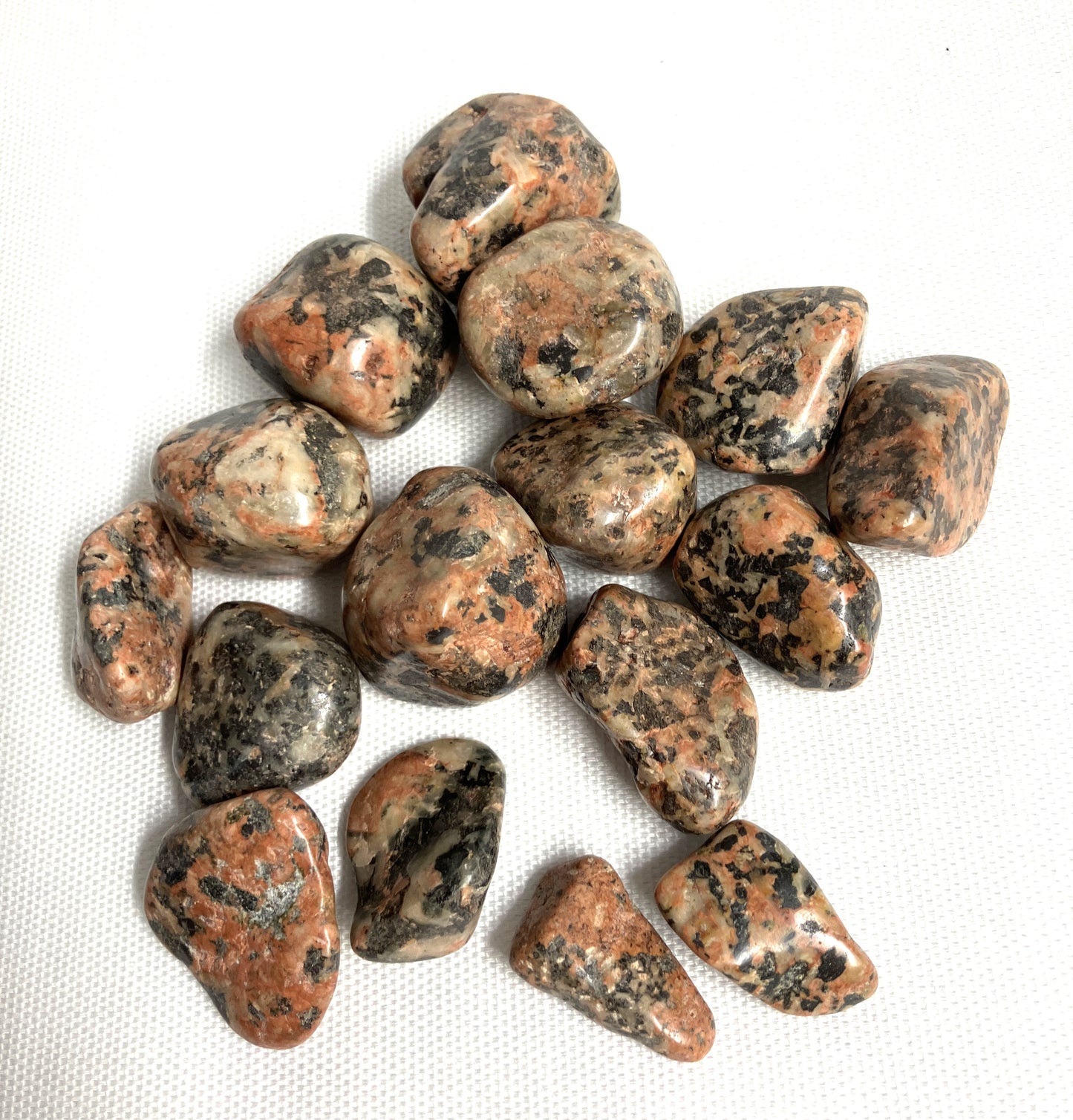 Collection of Orthoclase Crystals showing different colors and patterns on a white fabric background