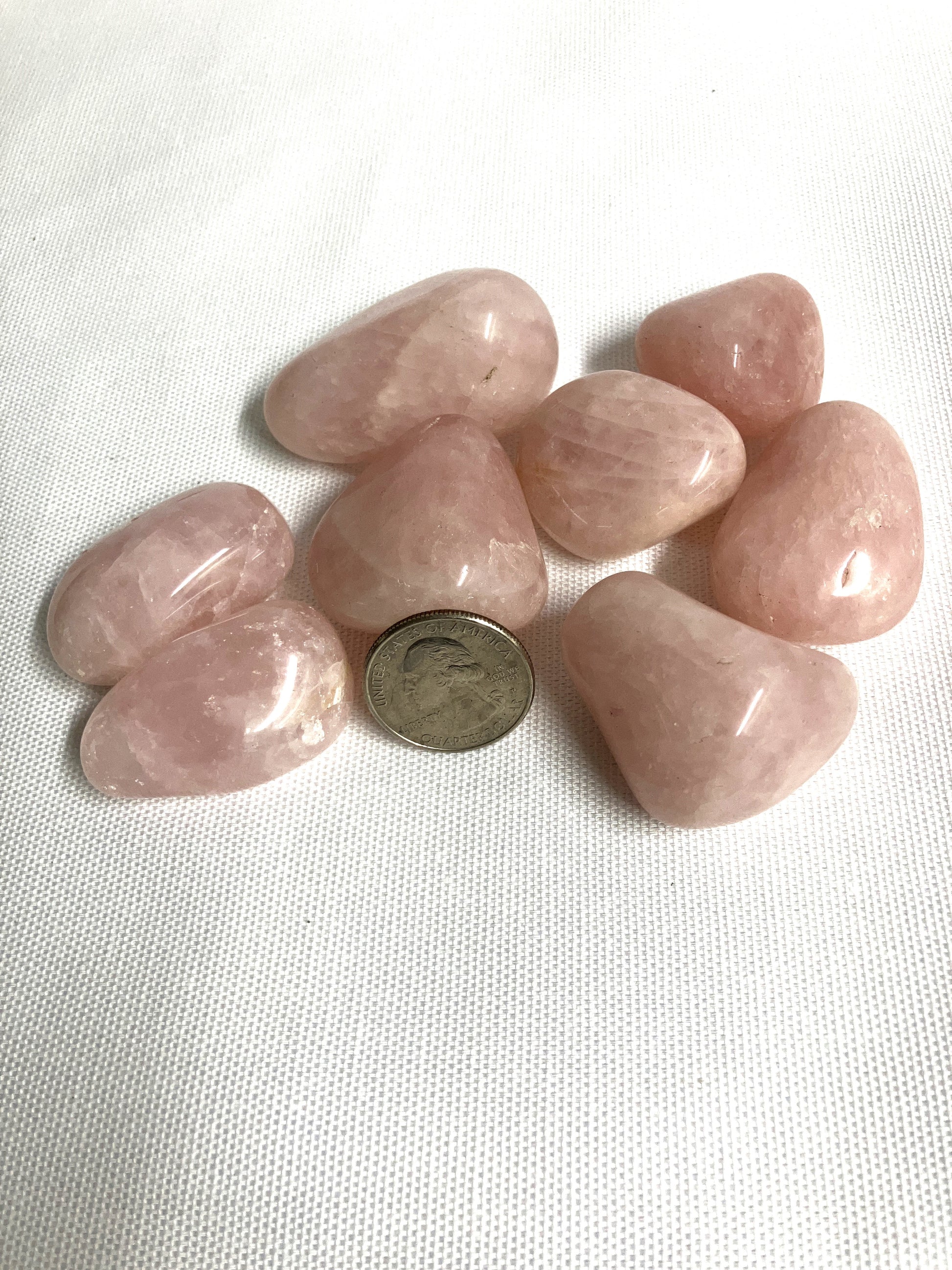 Rose Quartz Crystals on a white background with a quarter for scale