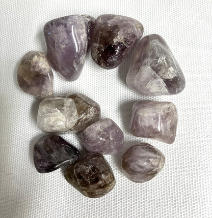 A grouping of Super Seven Crystals aka Melody's Stone on a white fabric background