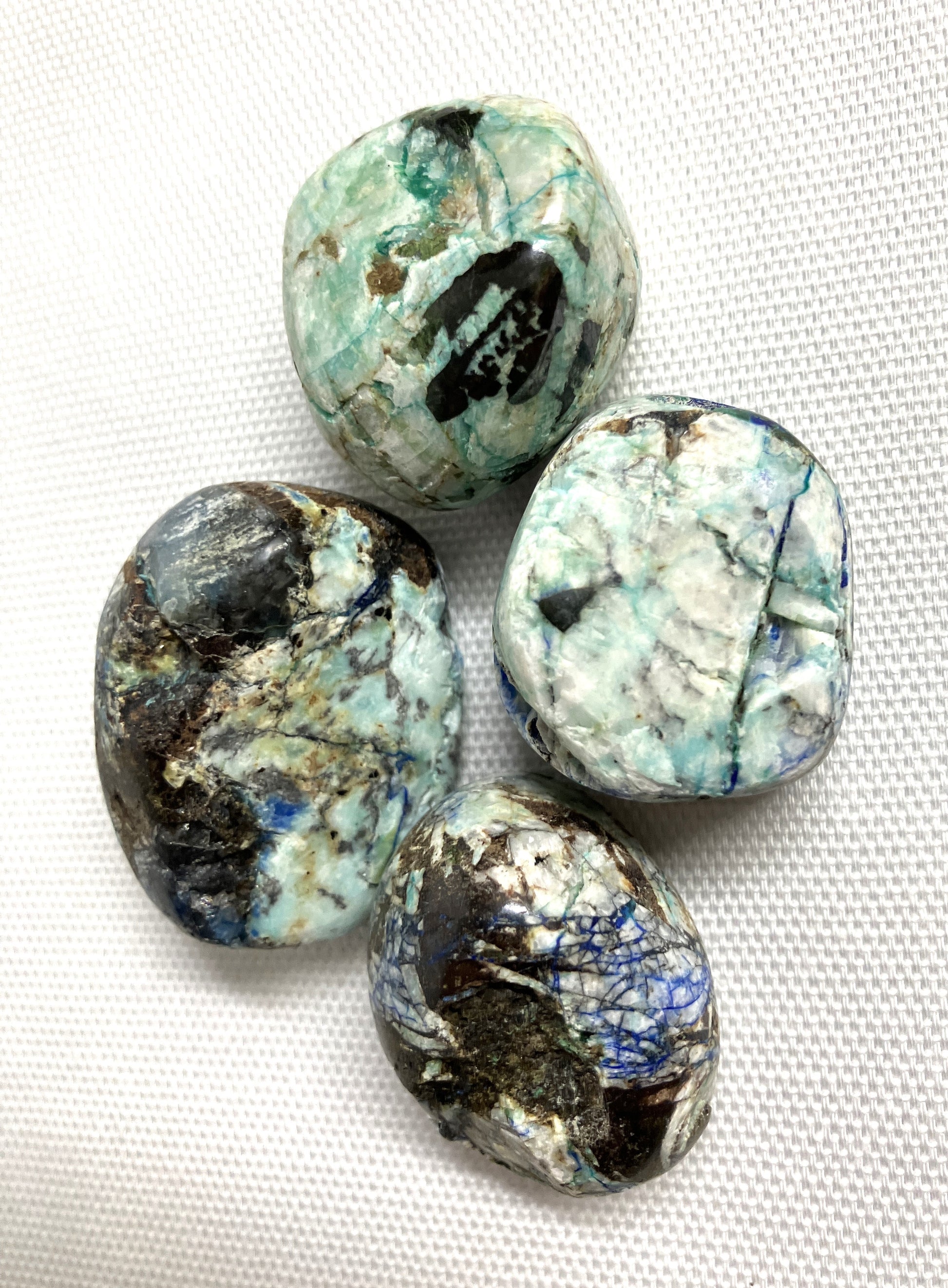 Four Azurite and Malachite Crystals Close view on a textured white background