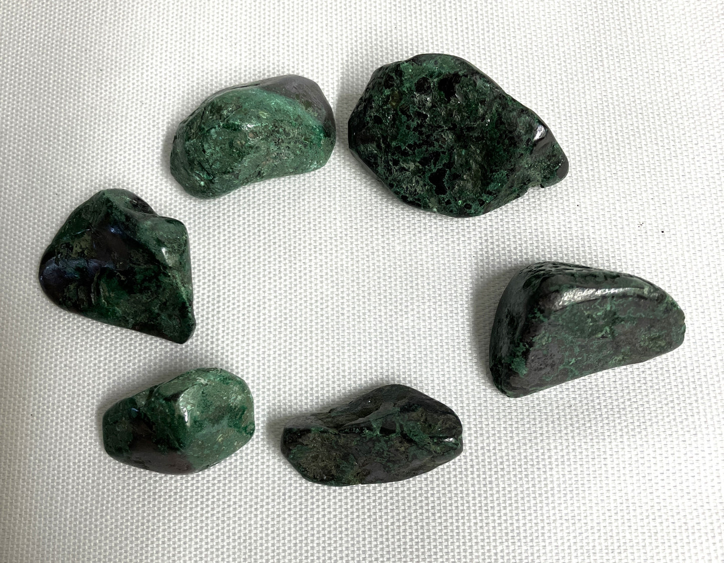 Six Cuprite Crystals showing the difference in color and pattern on a white fabric background