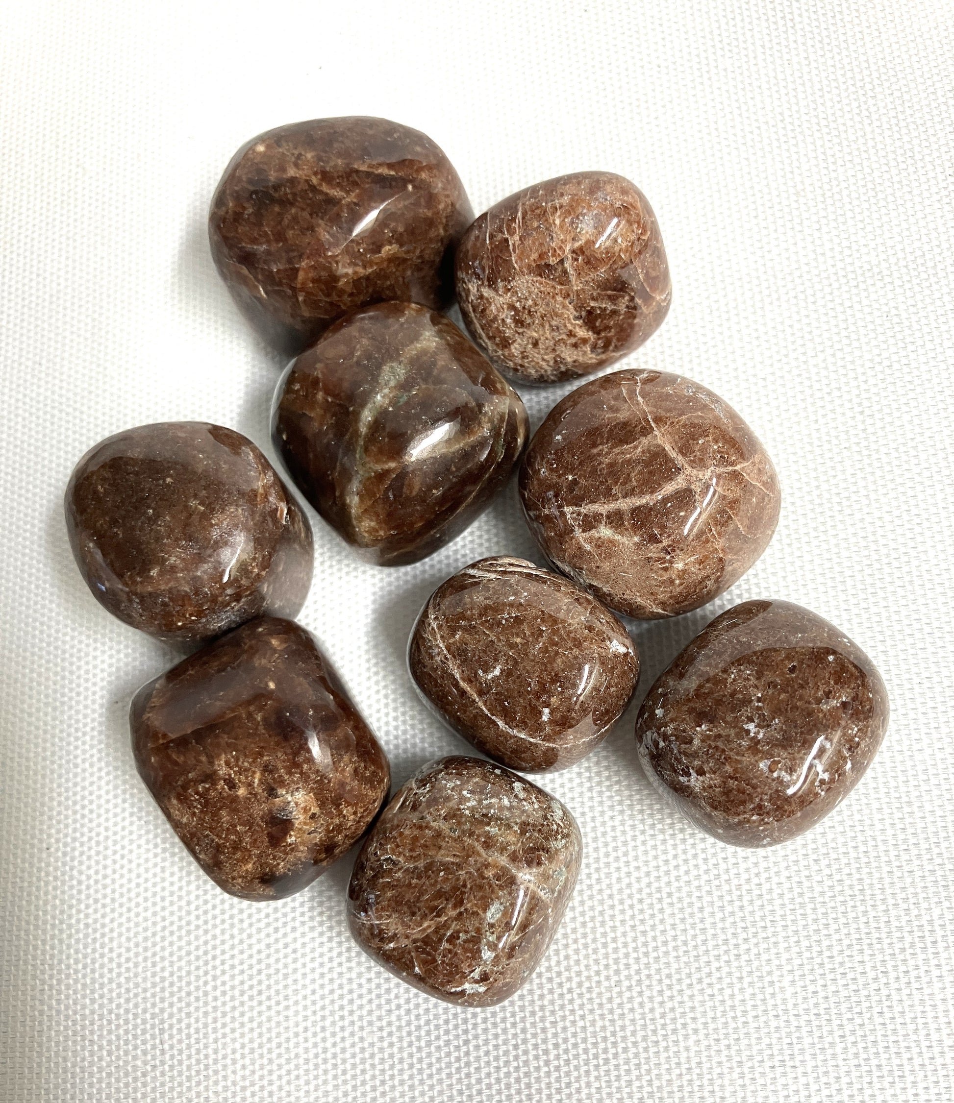Tumbled Hessonite Garnet Crystals on a white fabric background