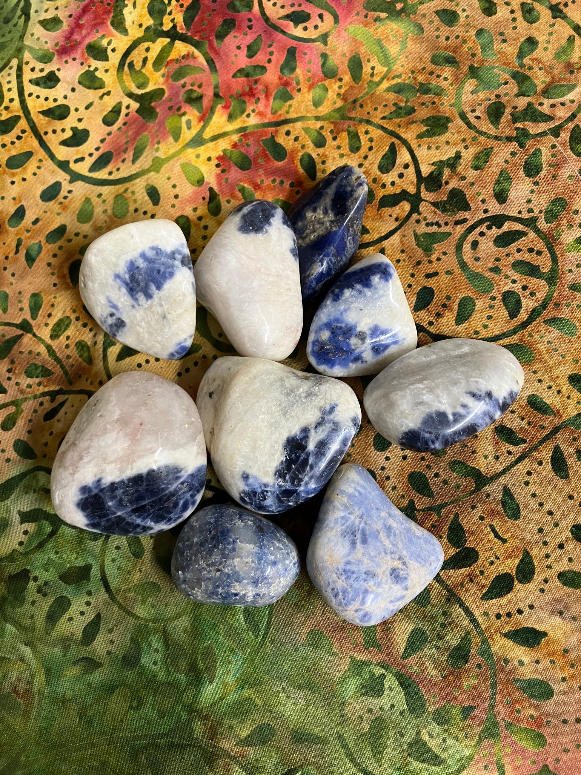 Tumbled Sodalite Crystals showing assorted patterns on a decorative fabric background