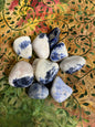 Tumbled Sodalite Crystals showing assorted patterns on a decorative fabric background