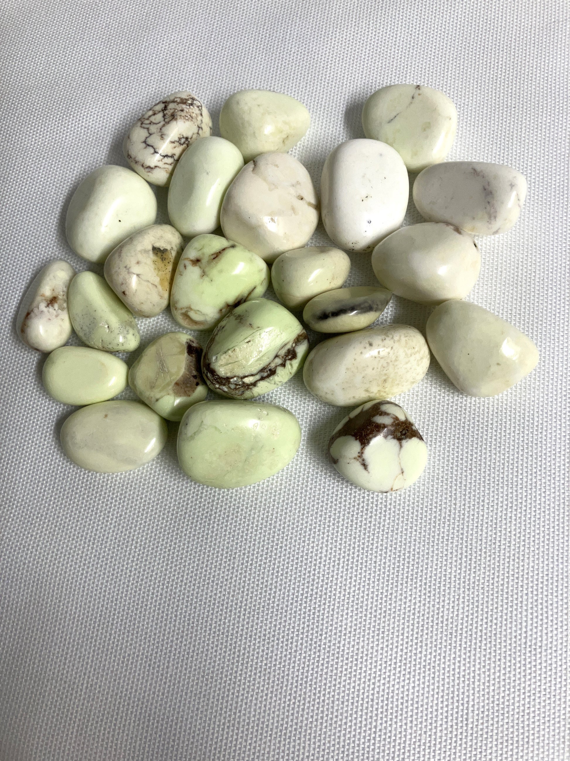 Front view of Lemon Chrysoprase Tumbled Crystals on a gray background