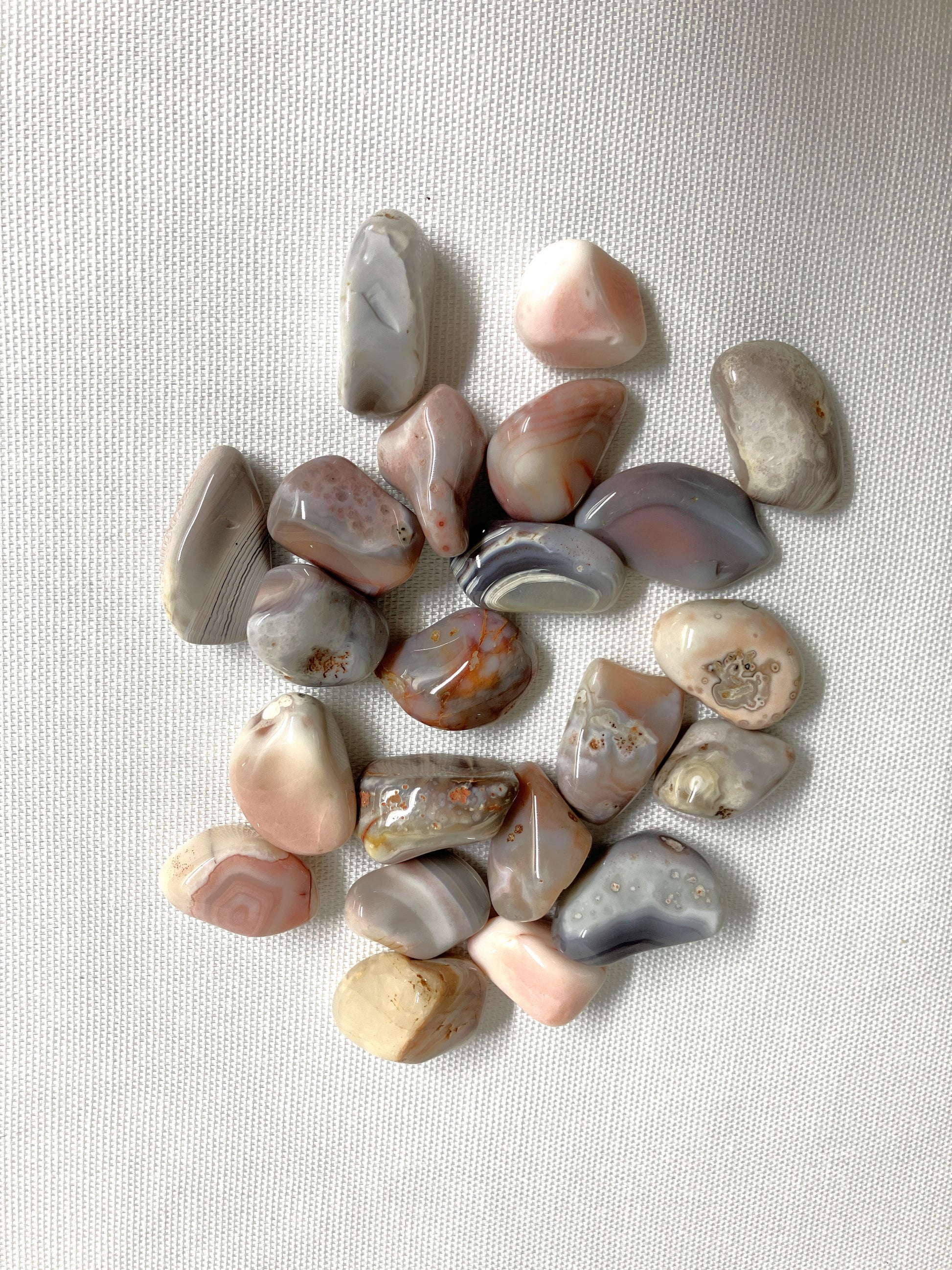 Collection of Botswana Agate Crystals showing the different patterns and colors on a light fabric background