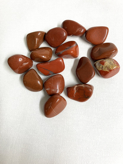 Red Jasper Crystals showing the variations of patterns on a white fabric background