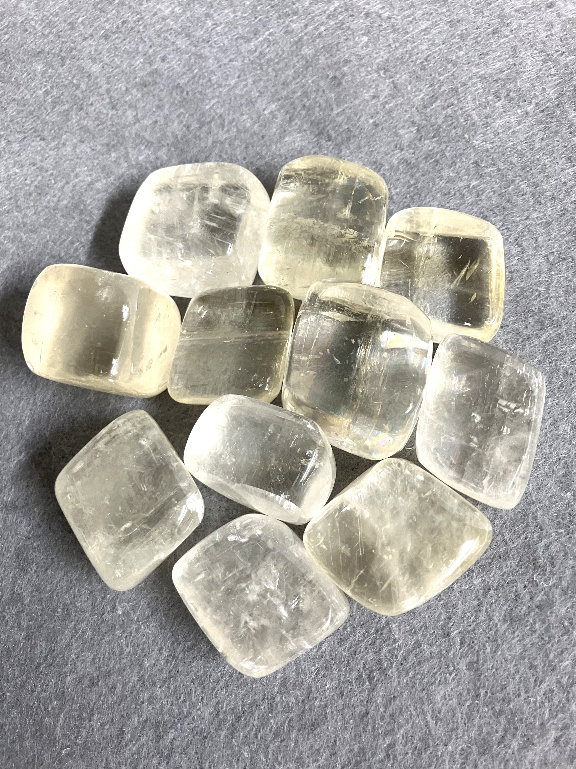 Yellow Calcite Tumbled Crystals shown on a gray surface