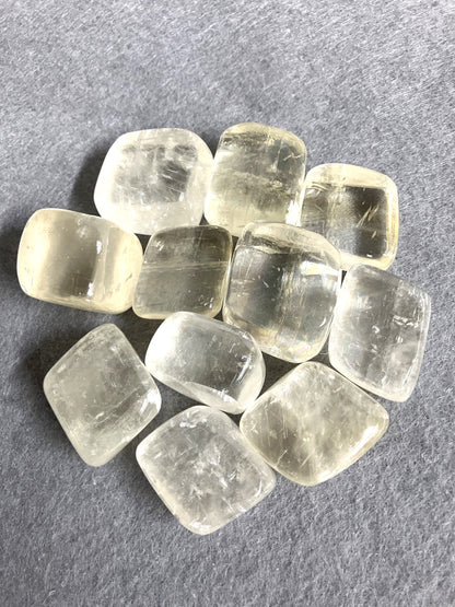 Yellow Calcite Tumbled Crystals shown on a gray surface