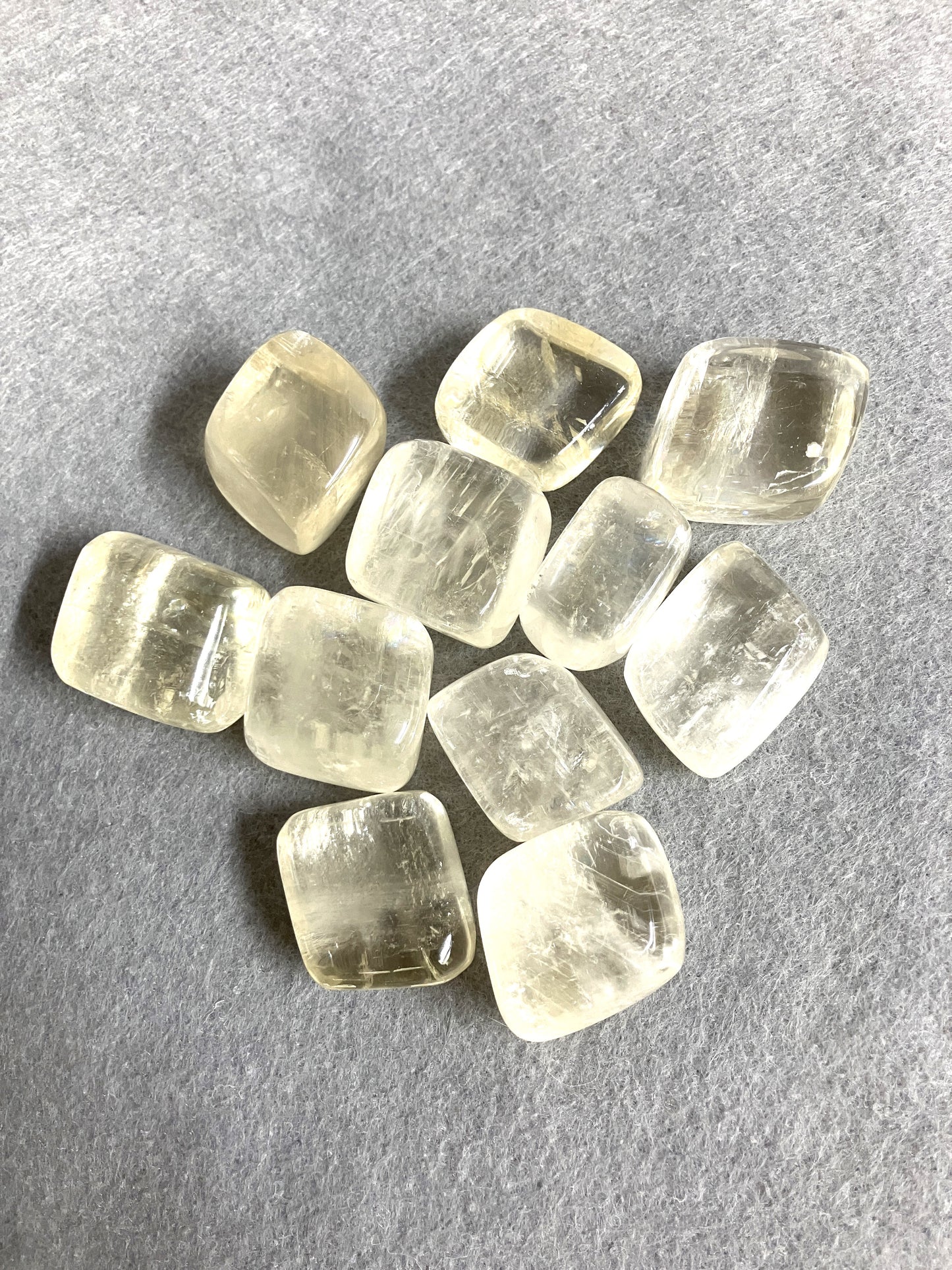 Yellow Calcite Tumbled Crystals in a croup on a gray background