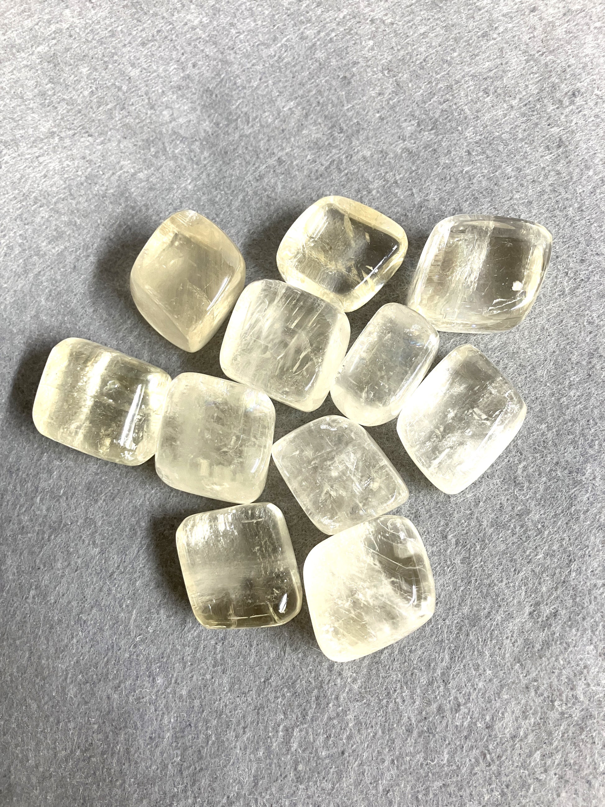 Yellow Calcite Tumbled Crystals in a croup on a gray background