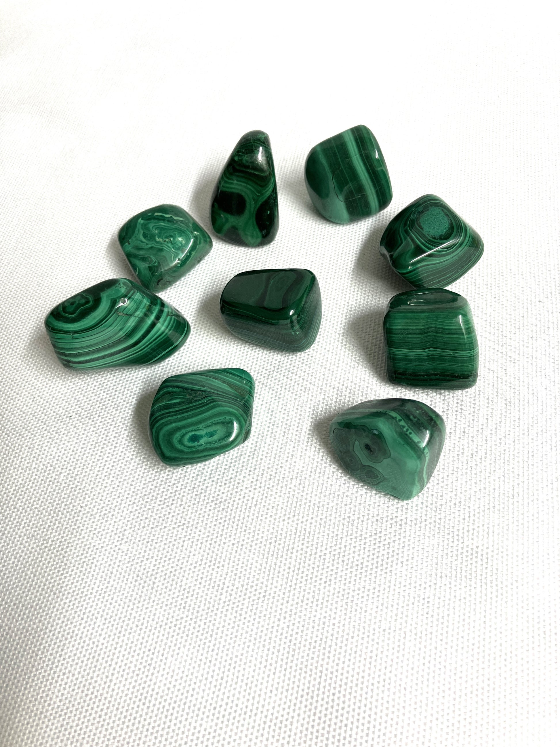Green malachite stones on a white fabric background
