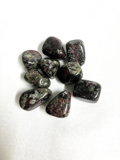 Collection of Eudialyte Tumbled Crystals showing the patterns and colors on a white background