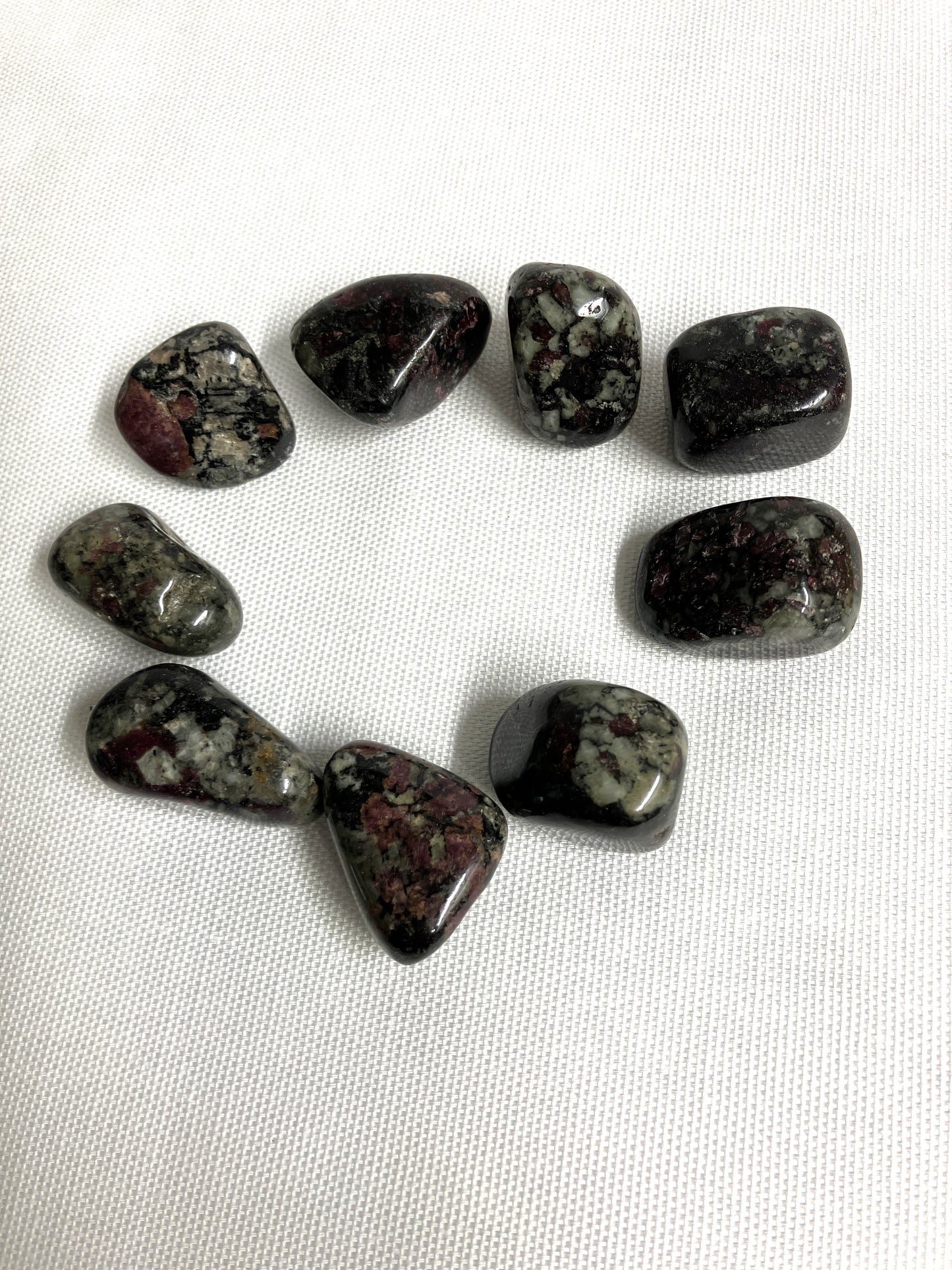 Group of Eudialyte Tumbled Crystals on a white fabric background