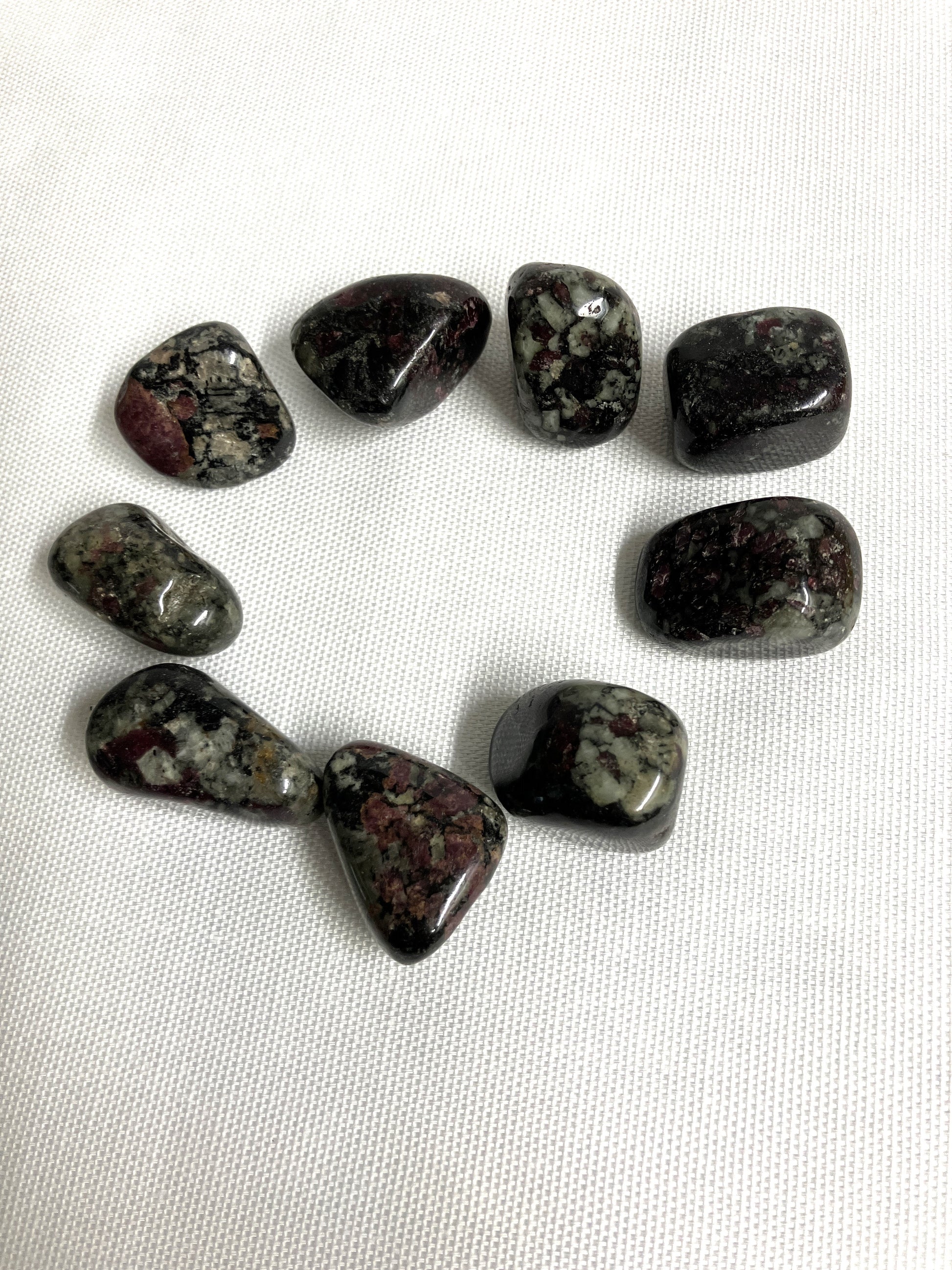 Group of Eudialyte Tumbled Crystals on a white fabric background