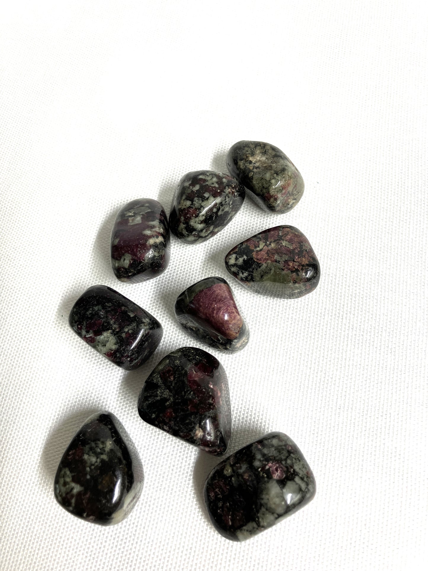 Eudialyte Tumbled Crystals on a white fabric background