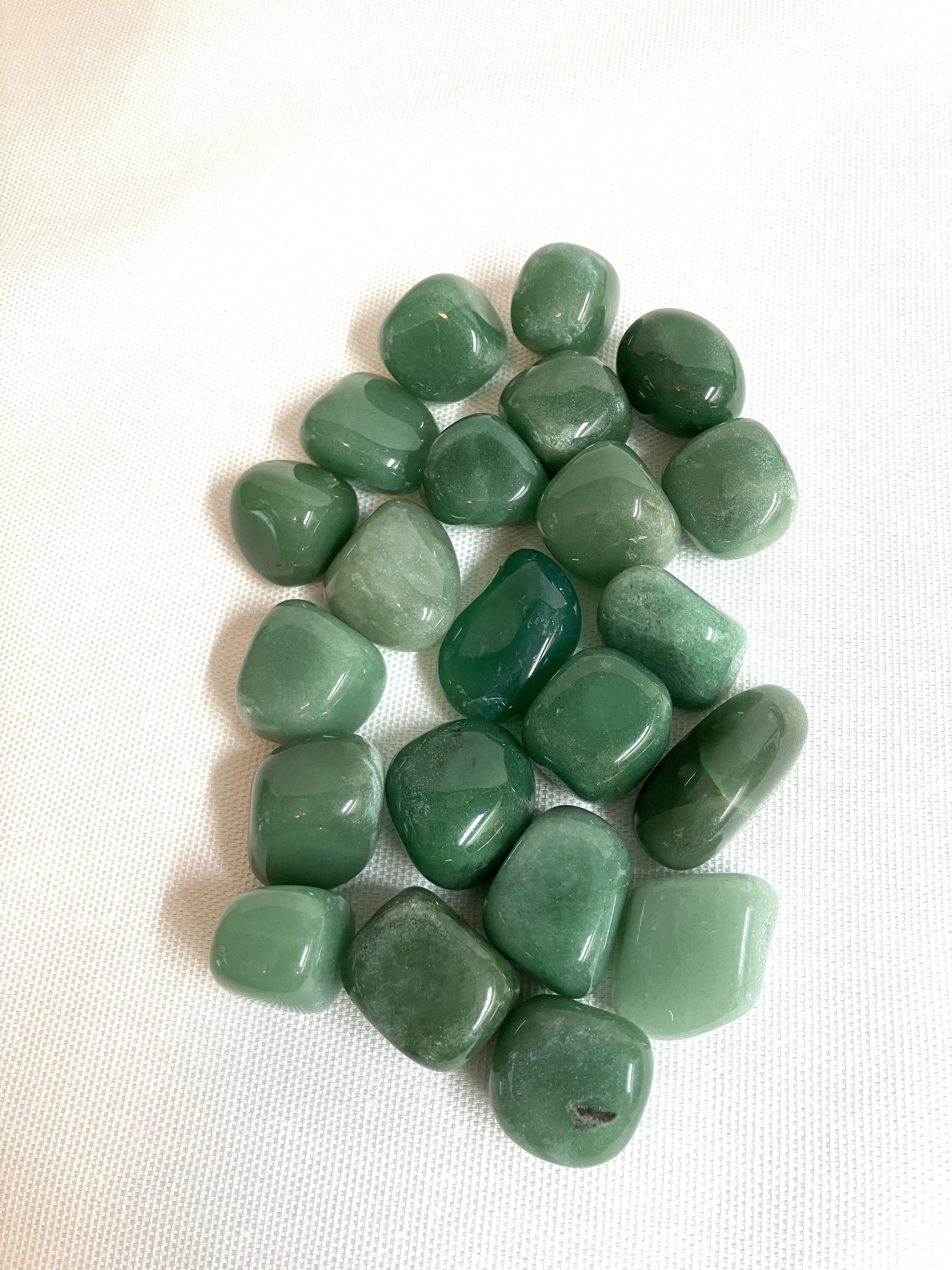 Back view of Green Aventurine Tumbled Crystals on a white fabric background