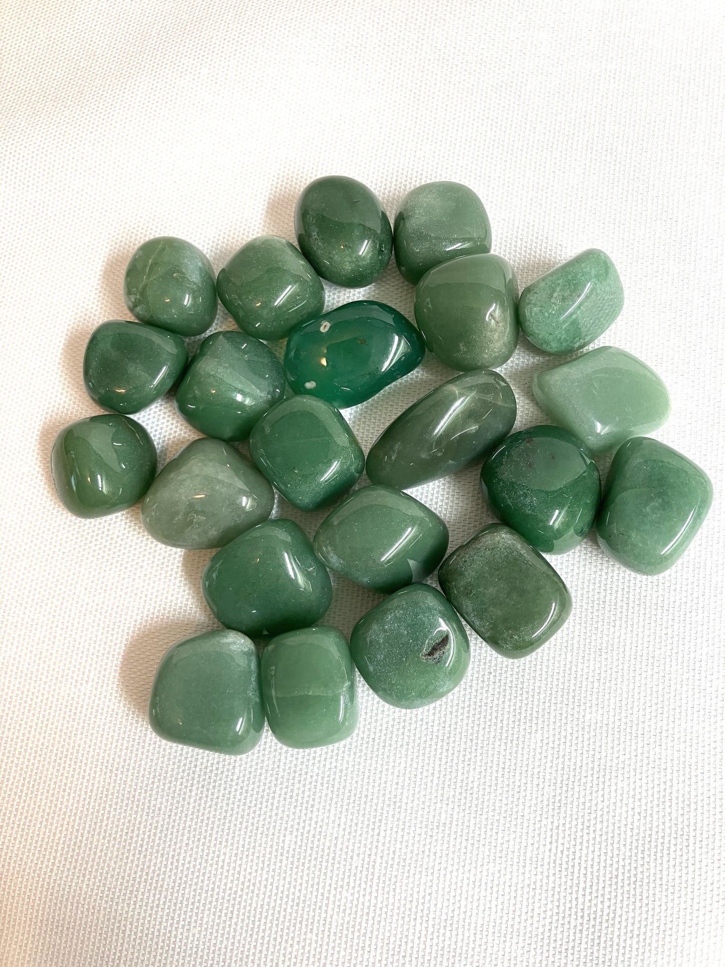 Green Aventurine Tumbled Crystals  front view on a white fabric background
